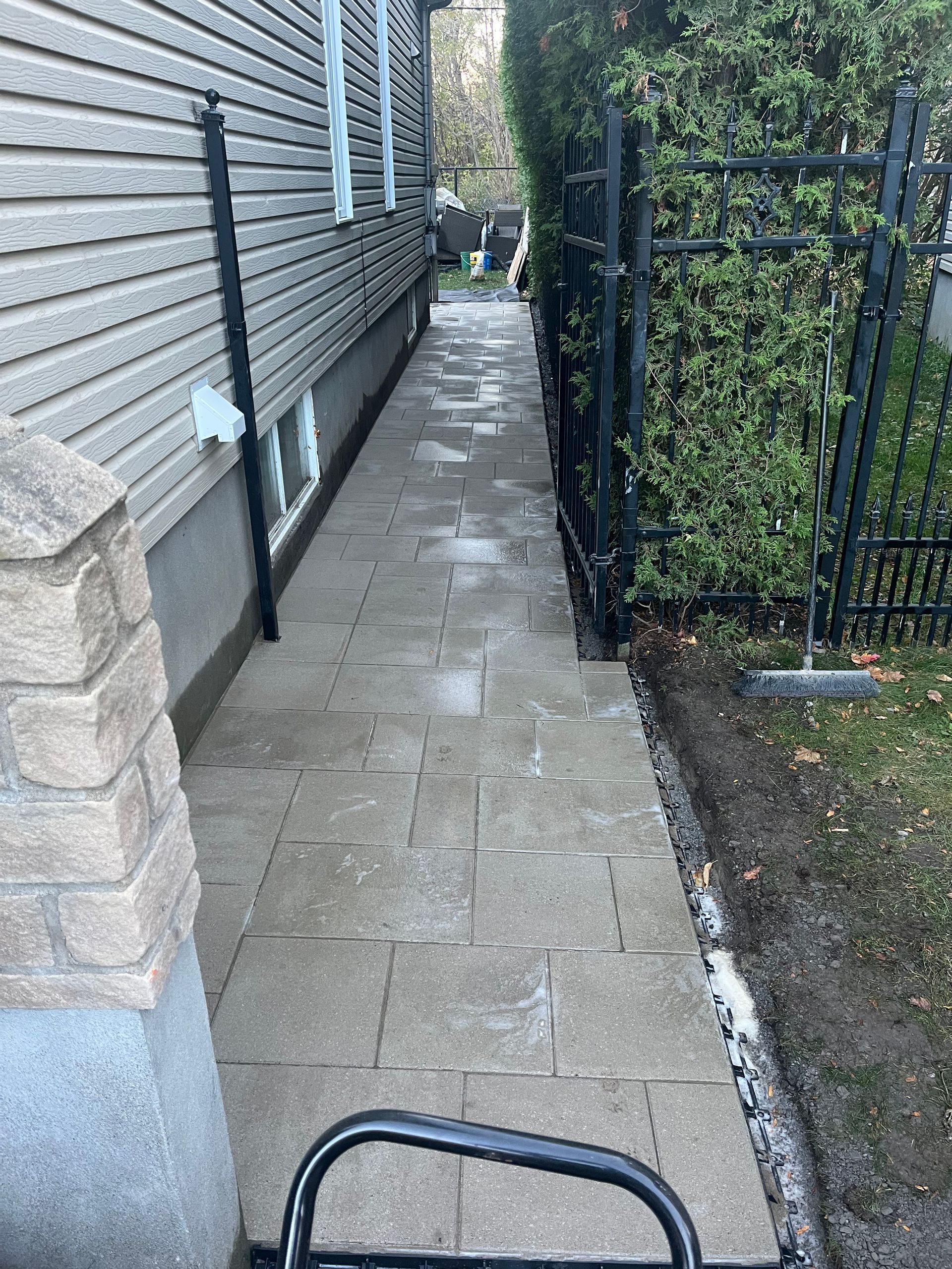 A sidewalk leading to a house next to a fence.