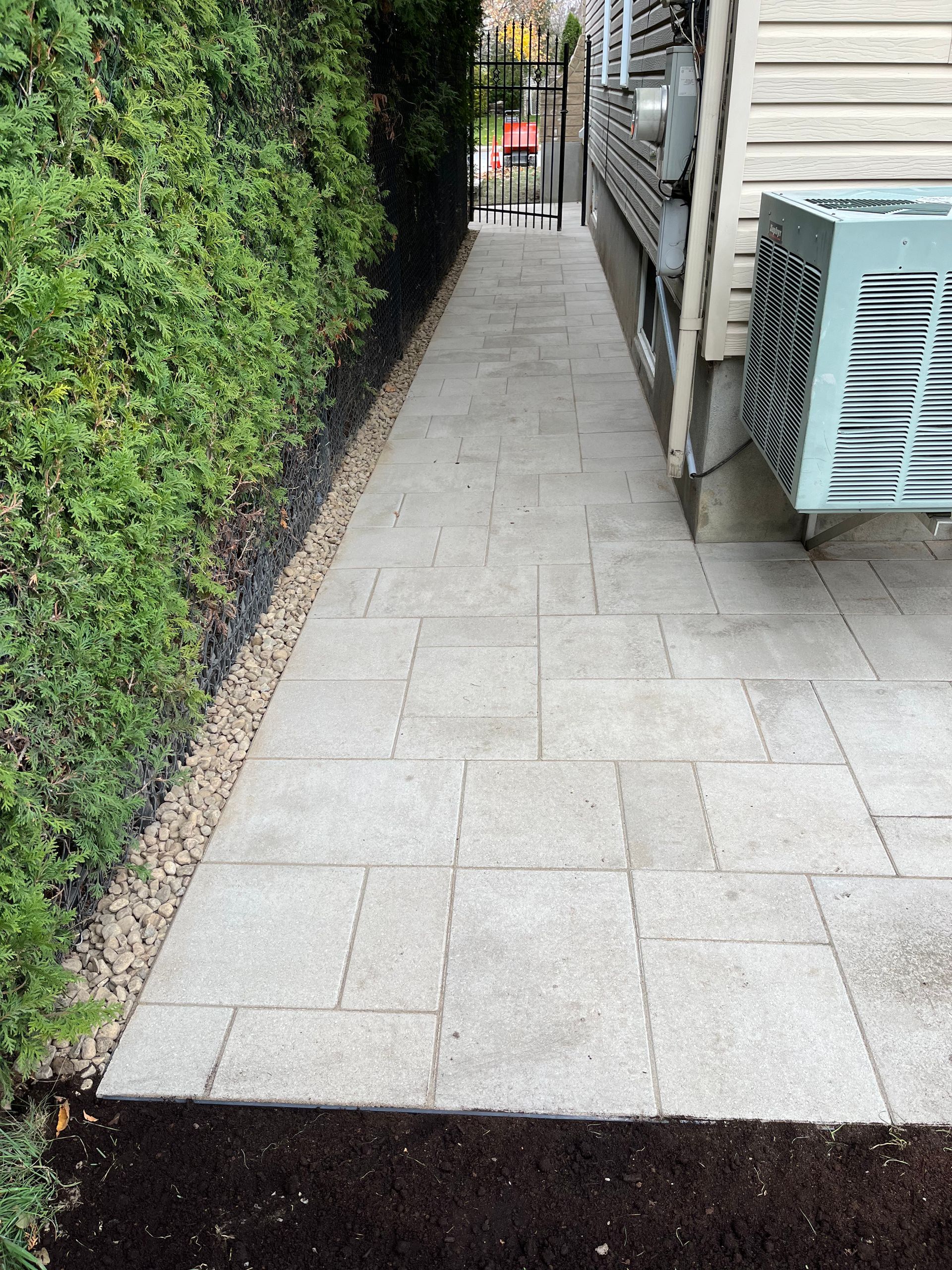 A sidewalk next to a house with a blue air conditioner