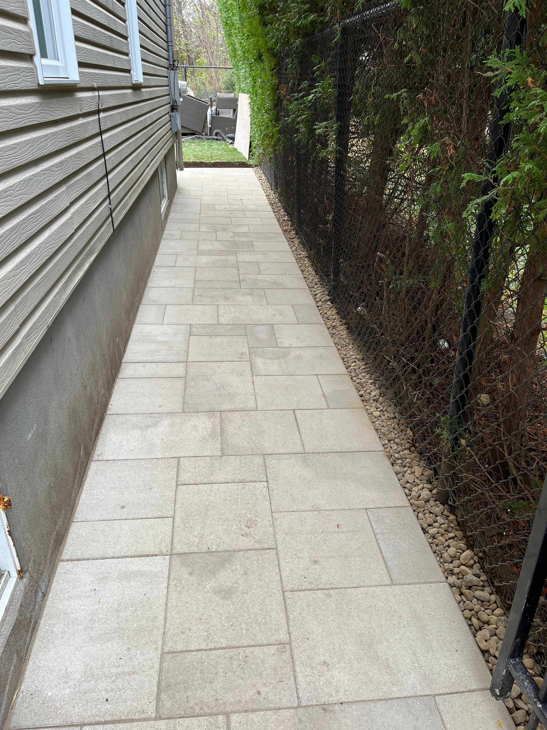 A sidewalk leading to a house next to a fence.