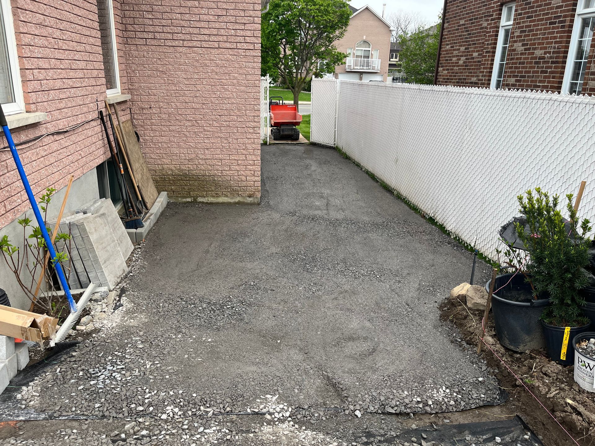 A driveway is being built in front of a brick house.