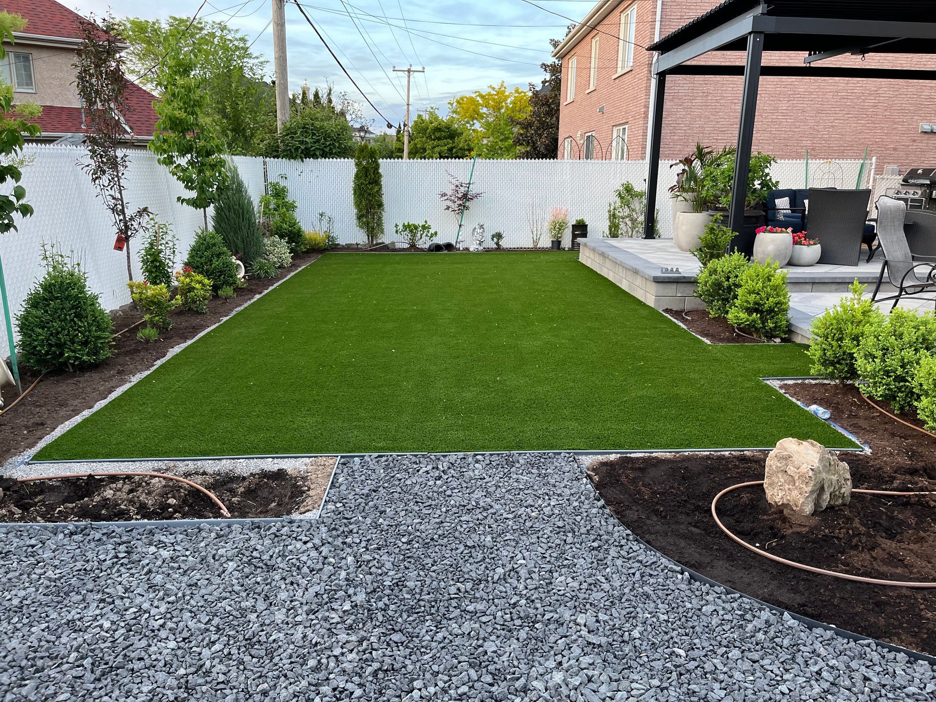 A backyard with a lush green lawn and a pergola.