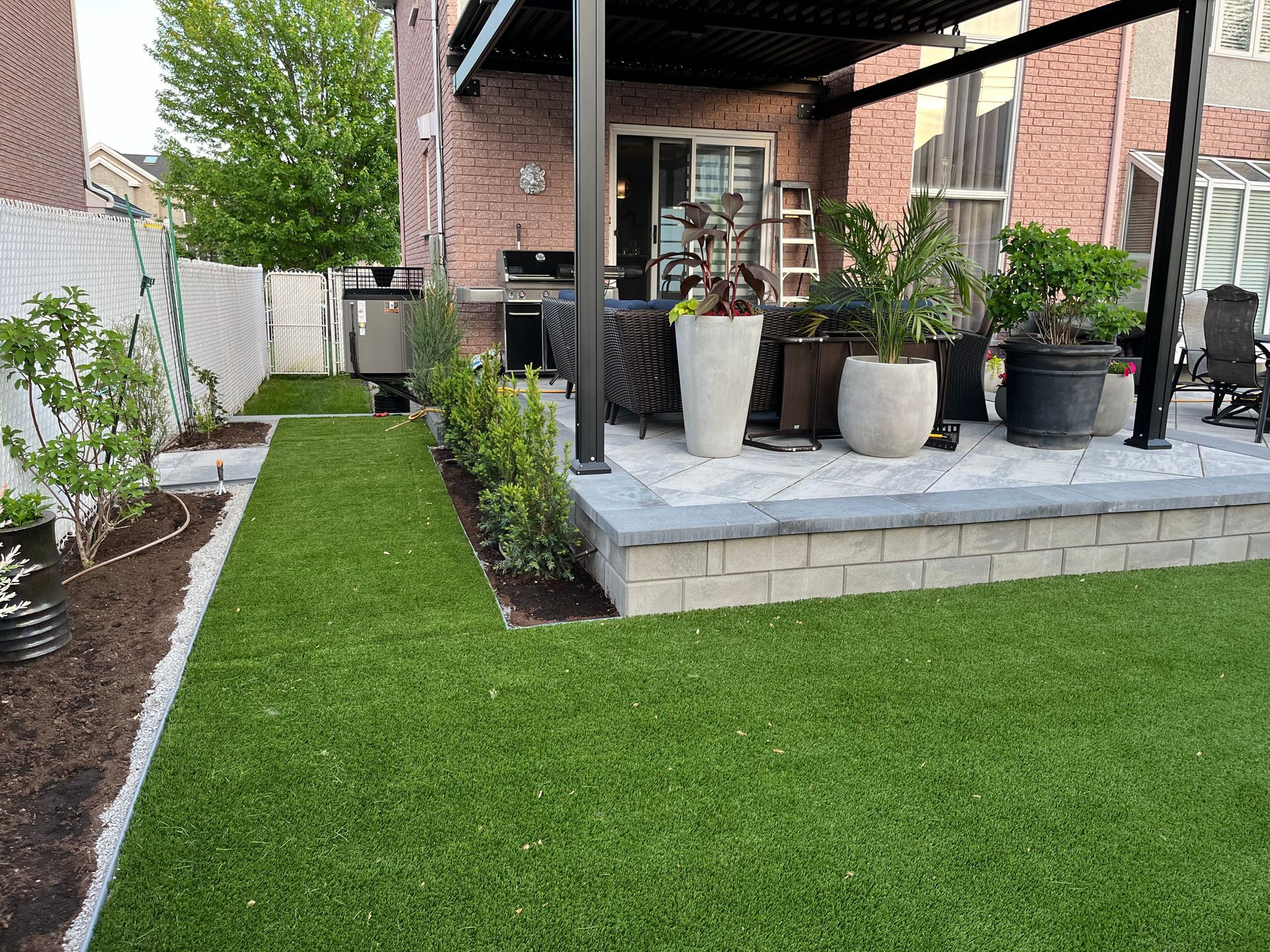 A backyard with a lush green lawn and potted plants.