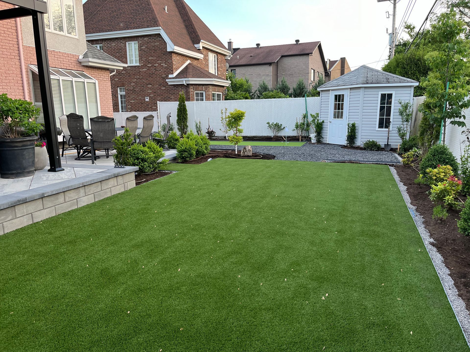 A backyard with a lush green lawn and a white shed.