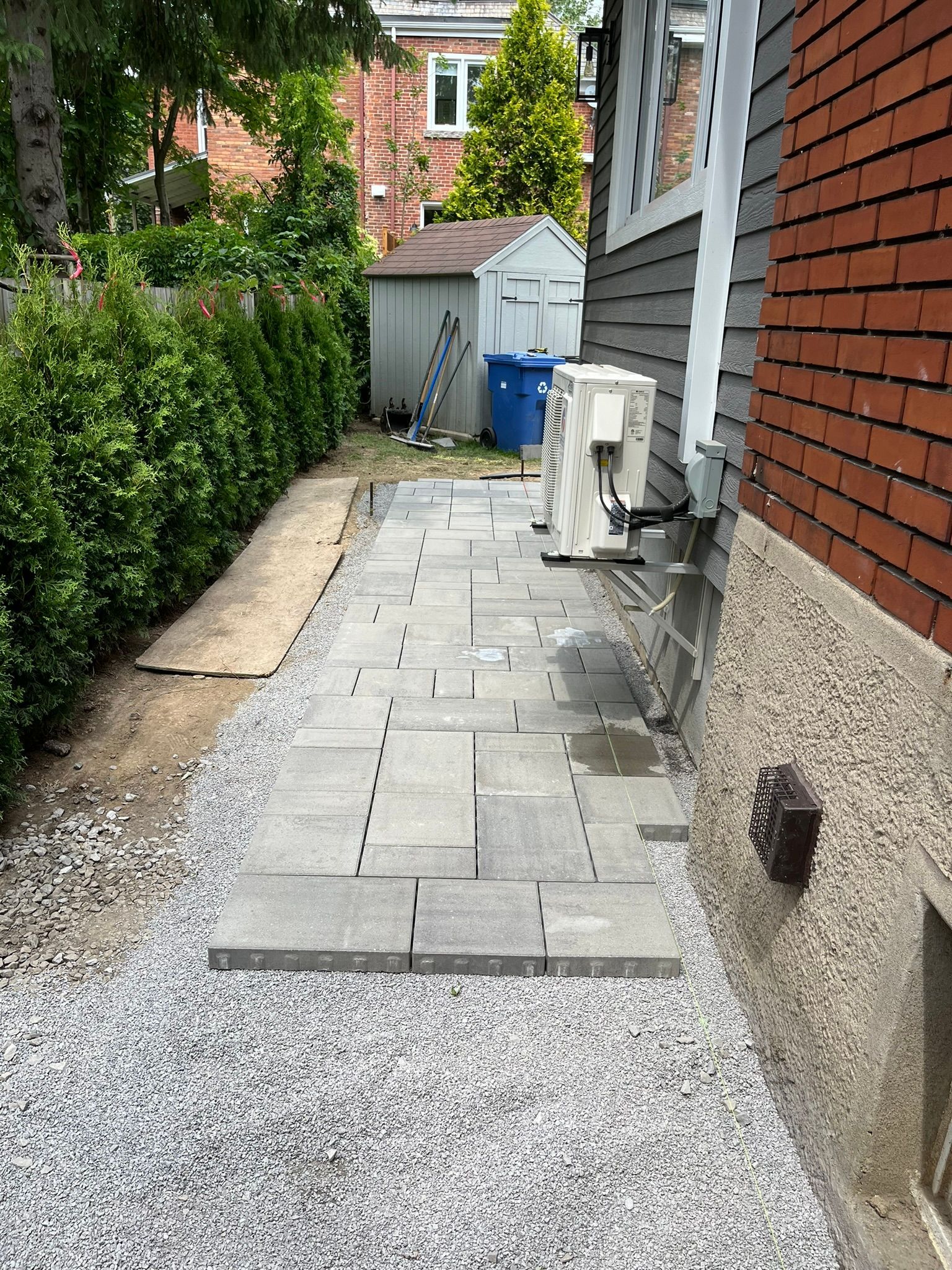 A sidewalk is being built in front of a brick house.