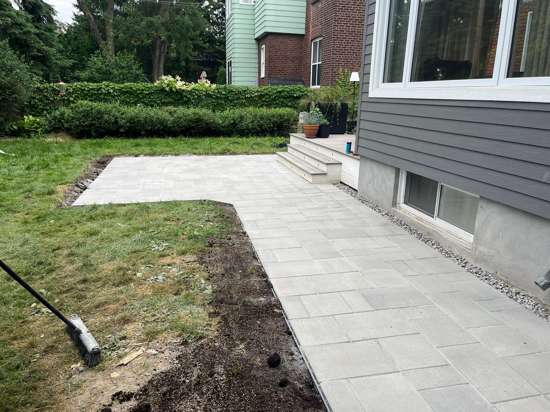 A person is raking dirt in front of a house.