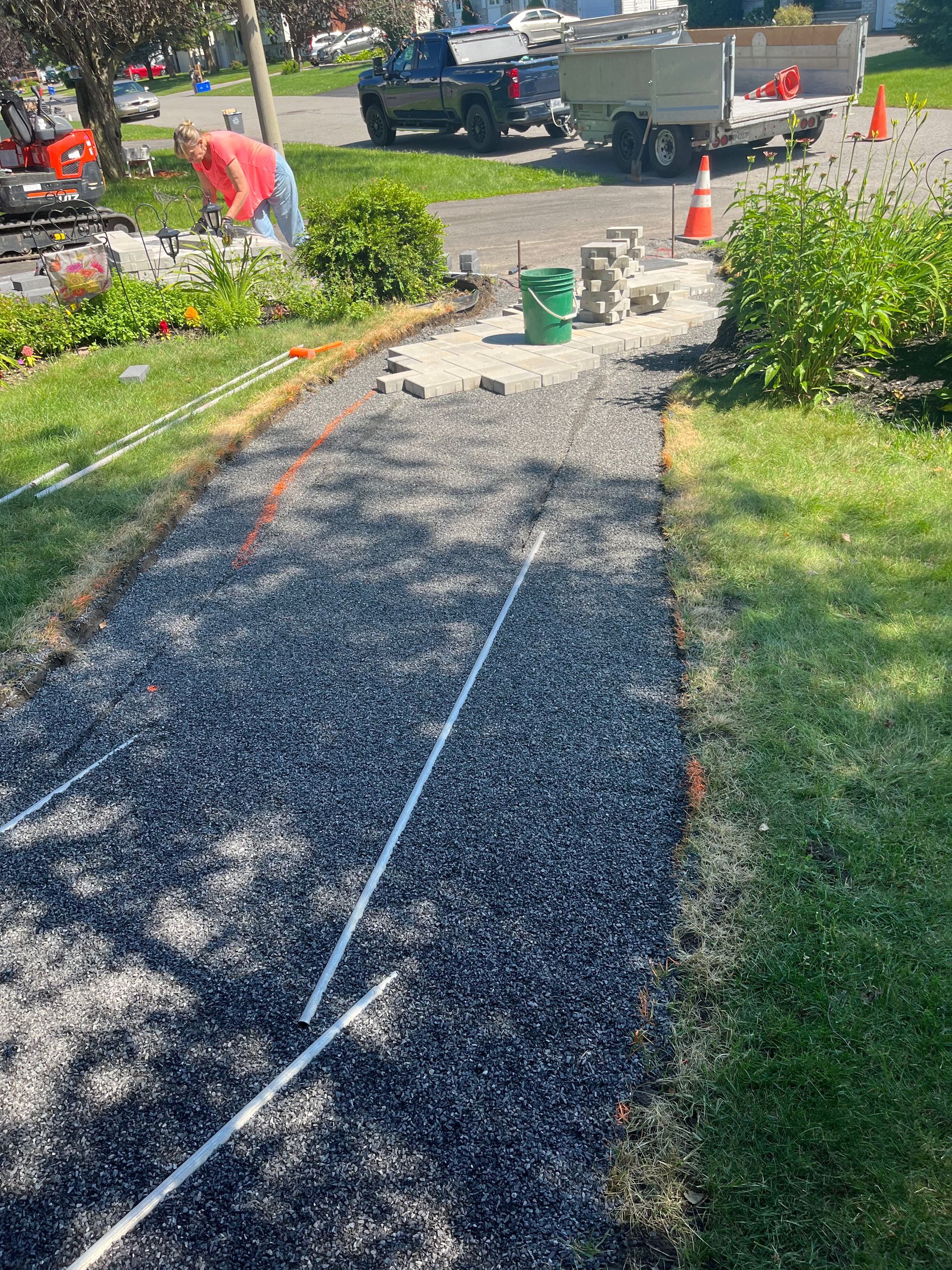 A man is working on a sidewalk in a yard.