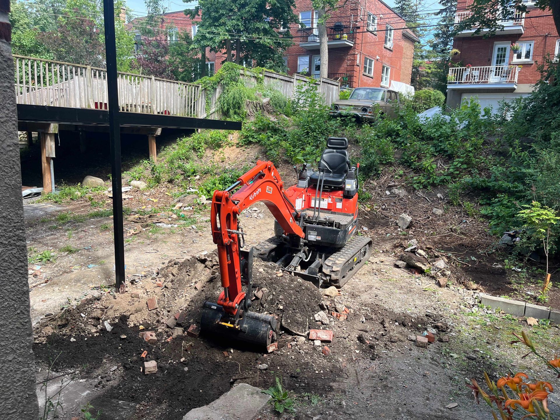 A small red excavator is digging a hole in a dirt field.