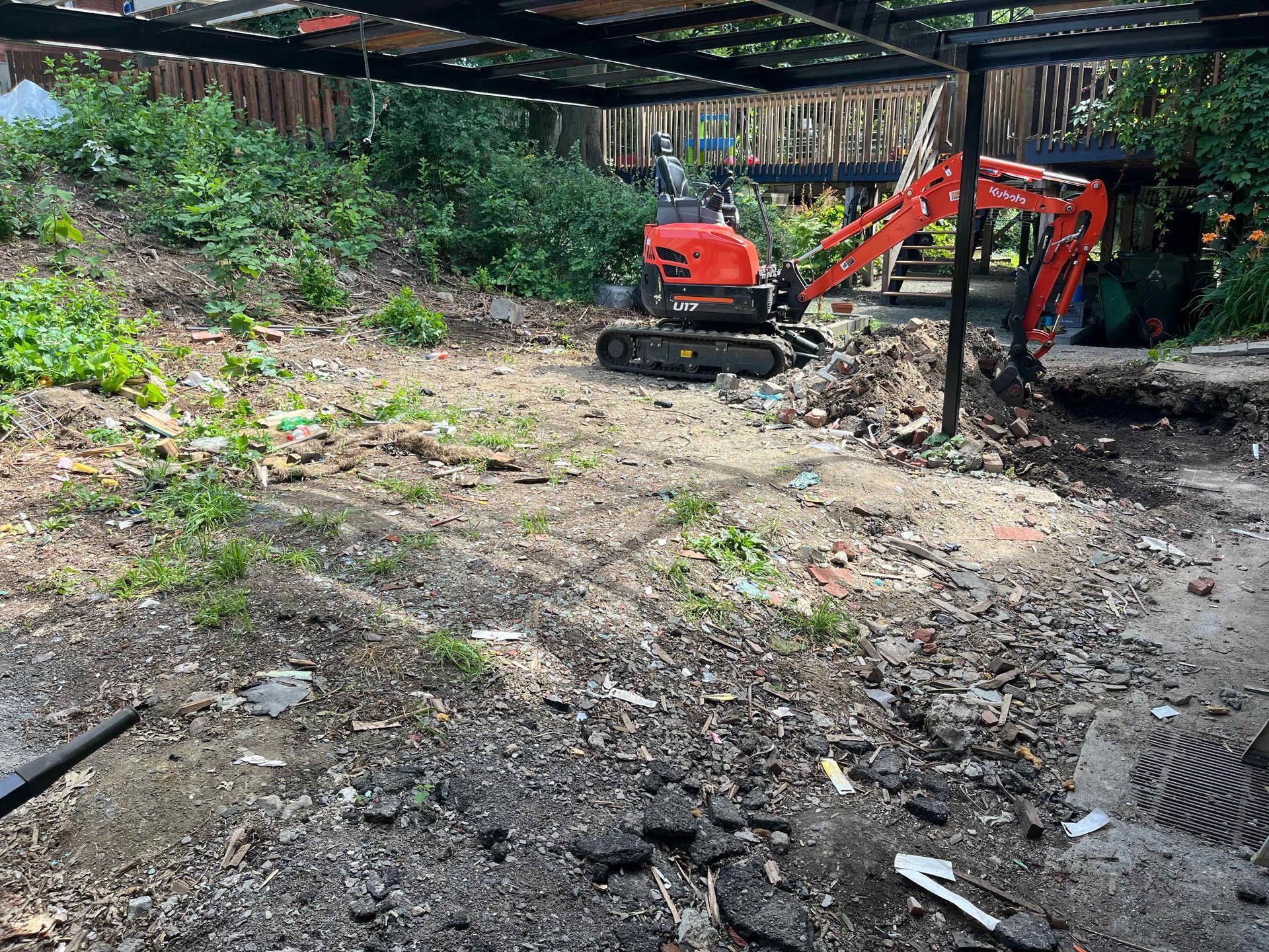 A small red excavator is digging a hole in a dirt field.