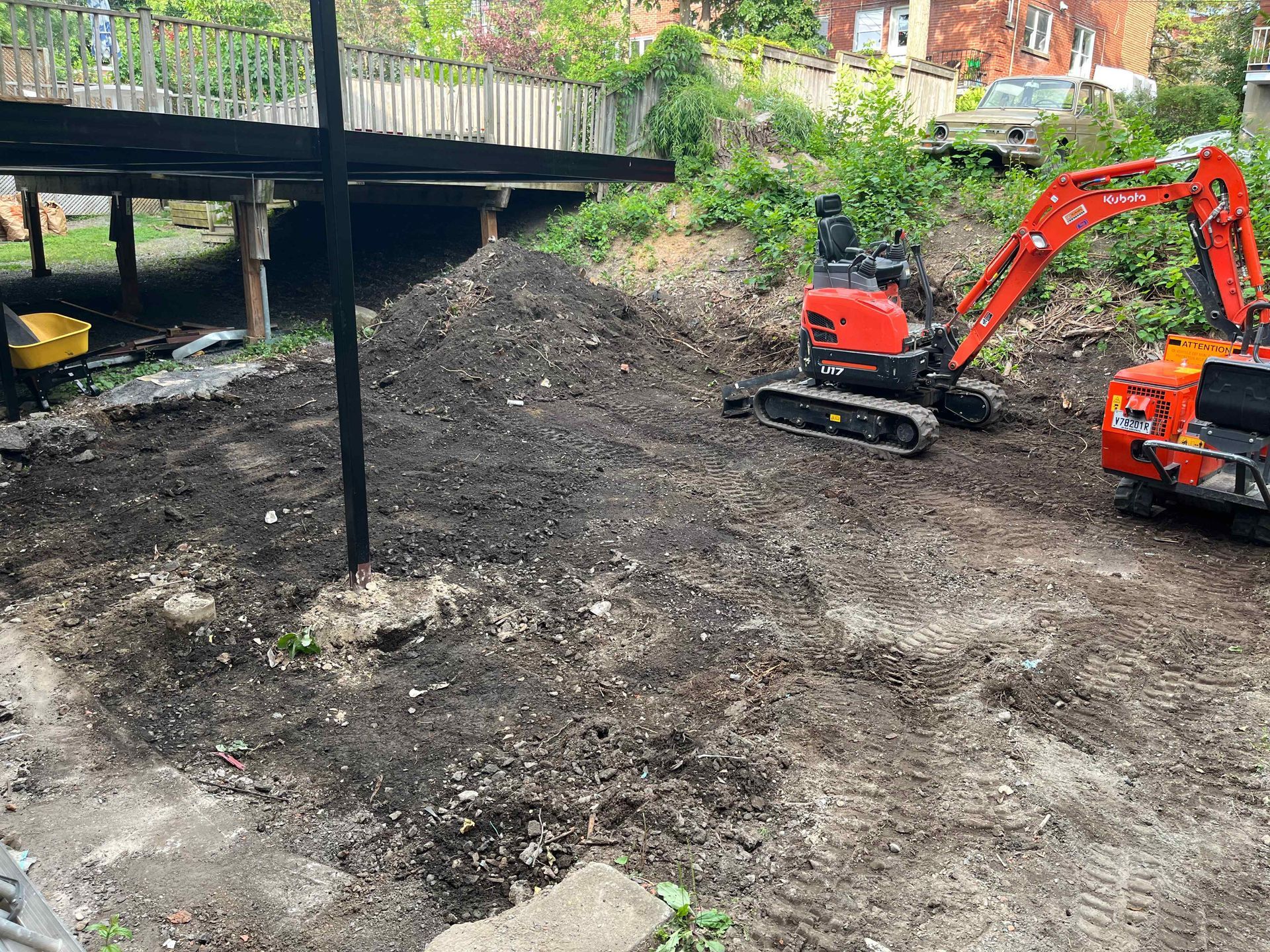 A red and orange excavator is moving dirt in a field.