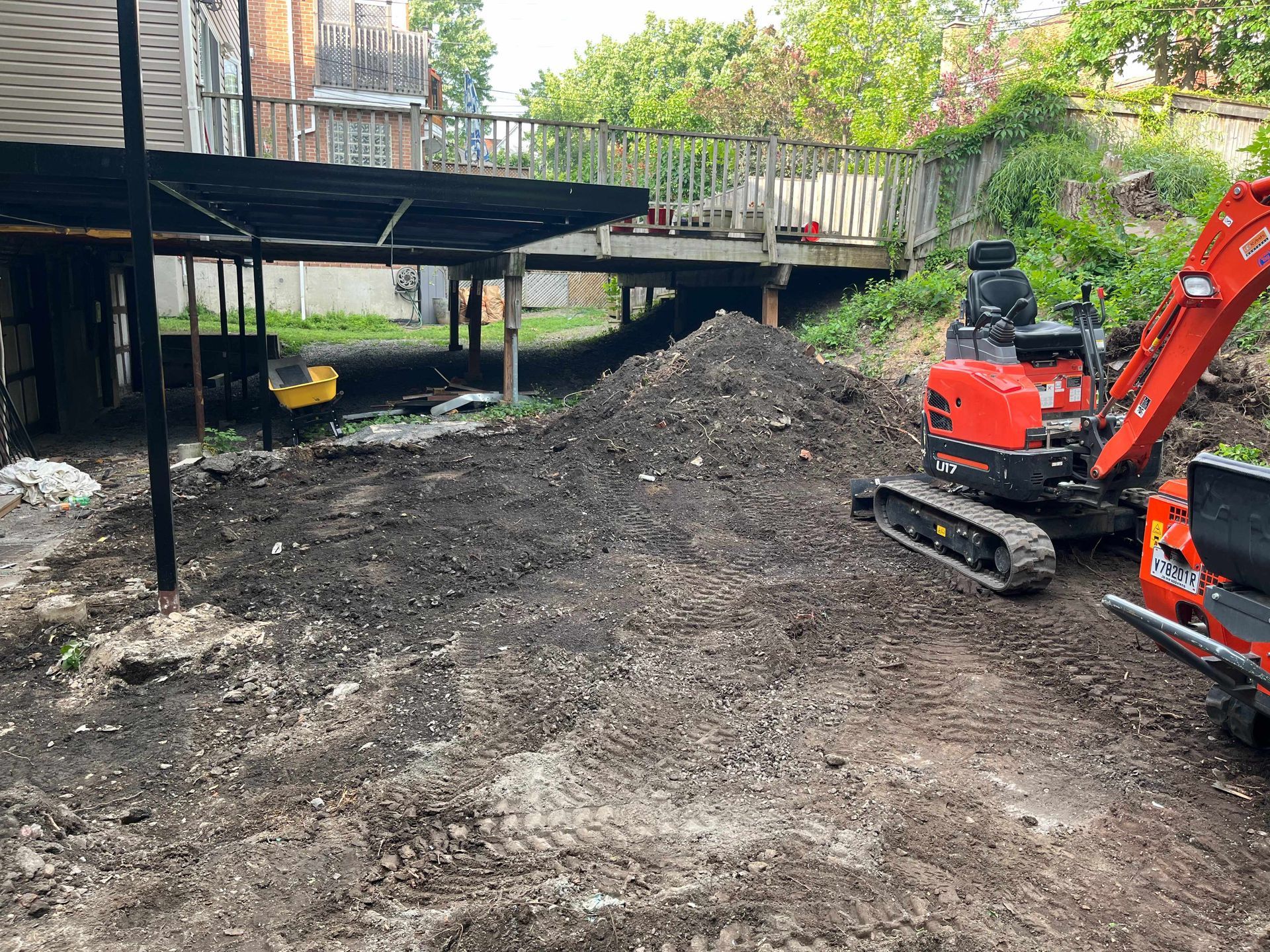 A small excavator is sitting in the dirt in front of a house.