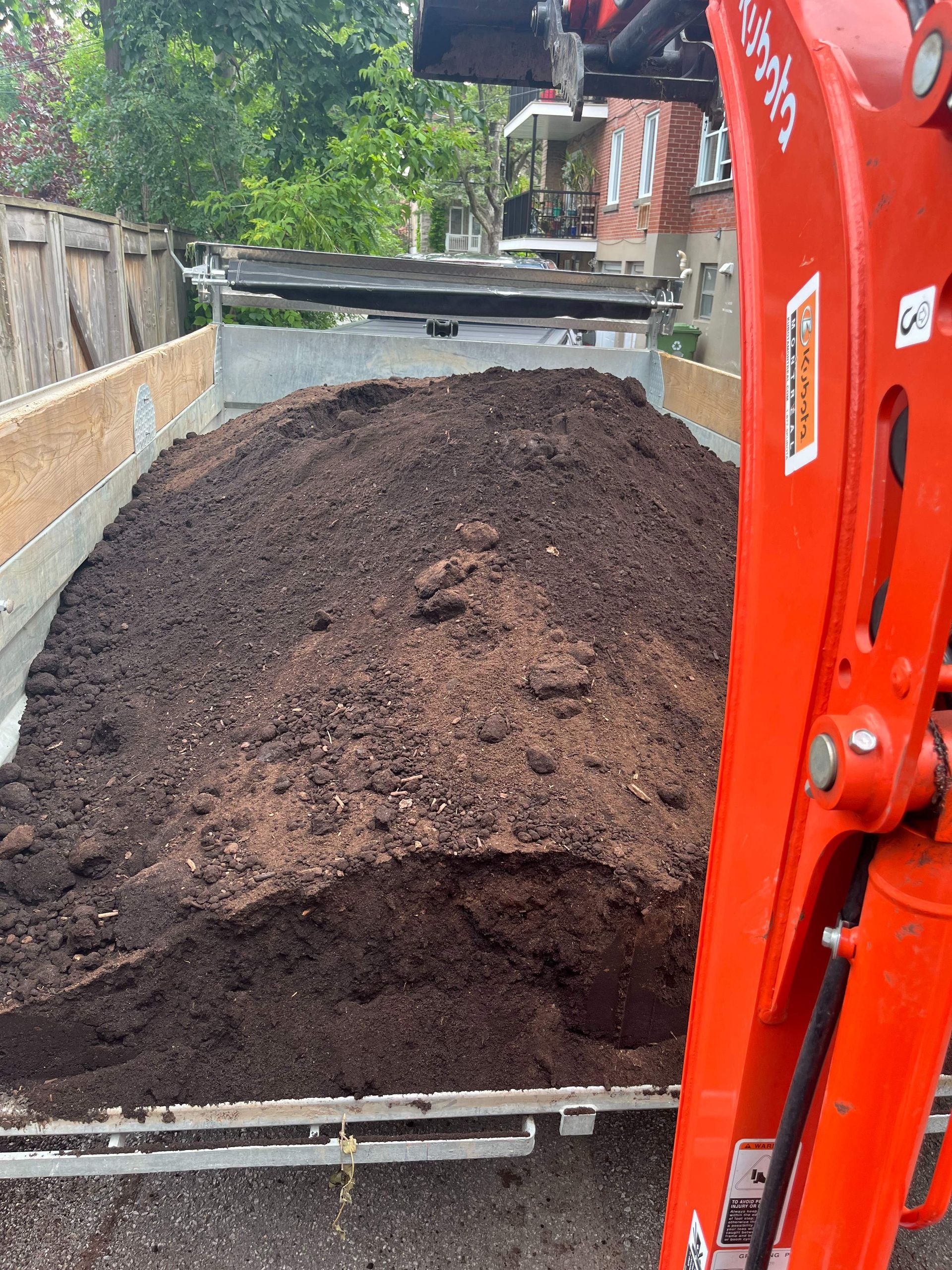 A large pile of dirt is being loaded into a truck.