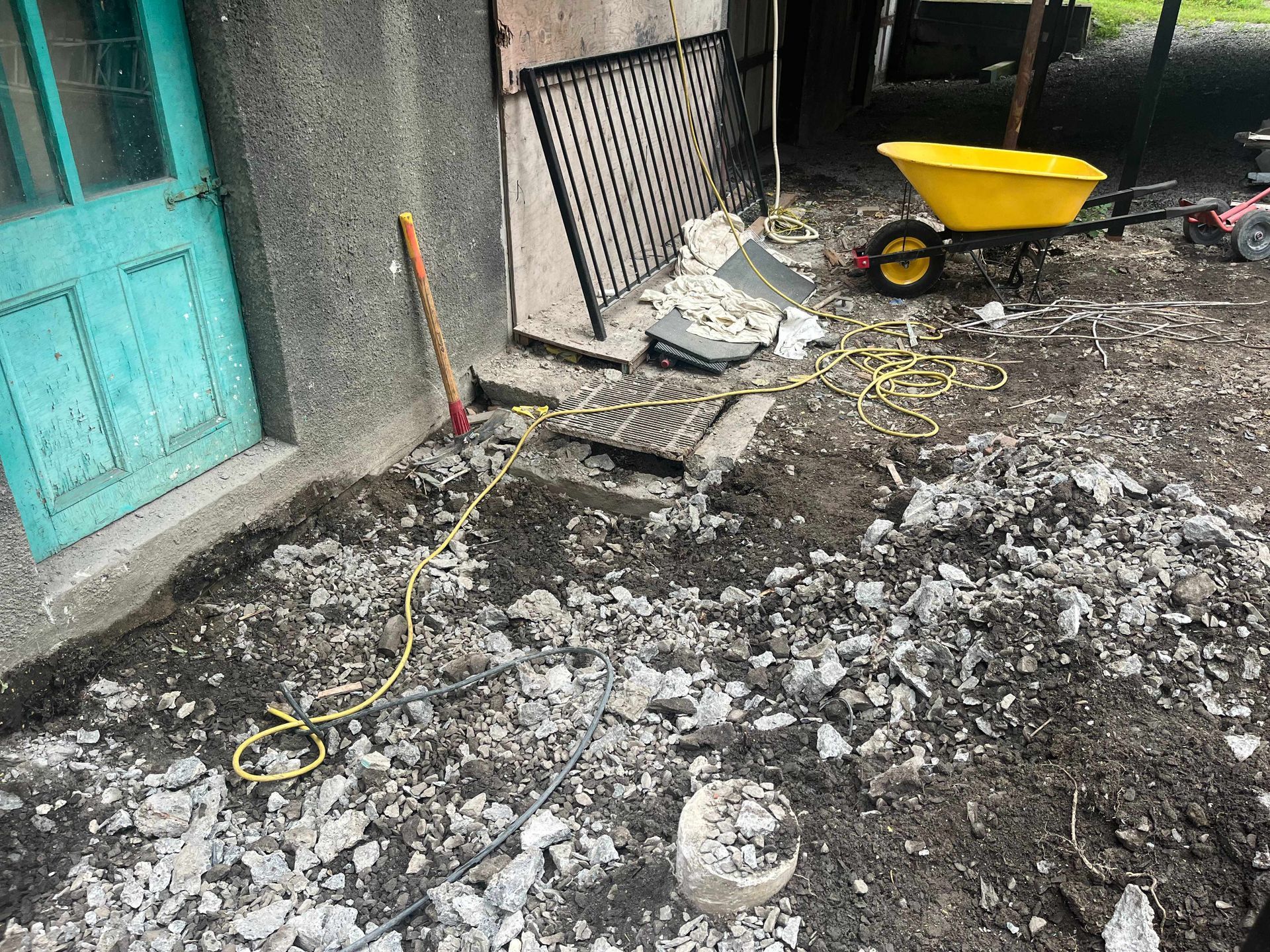 A yellow wheelbarrow is sitting on the ground next to a building.