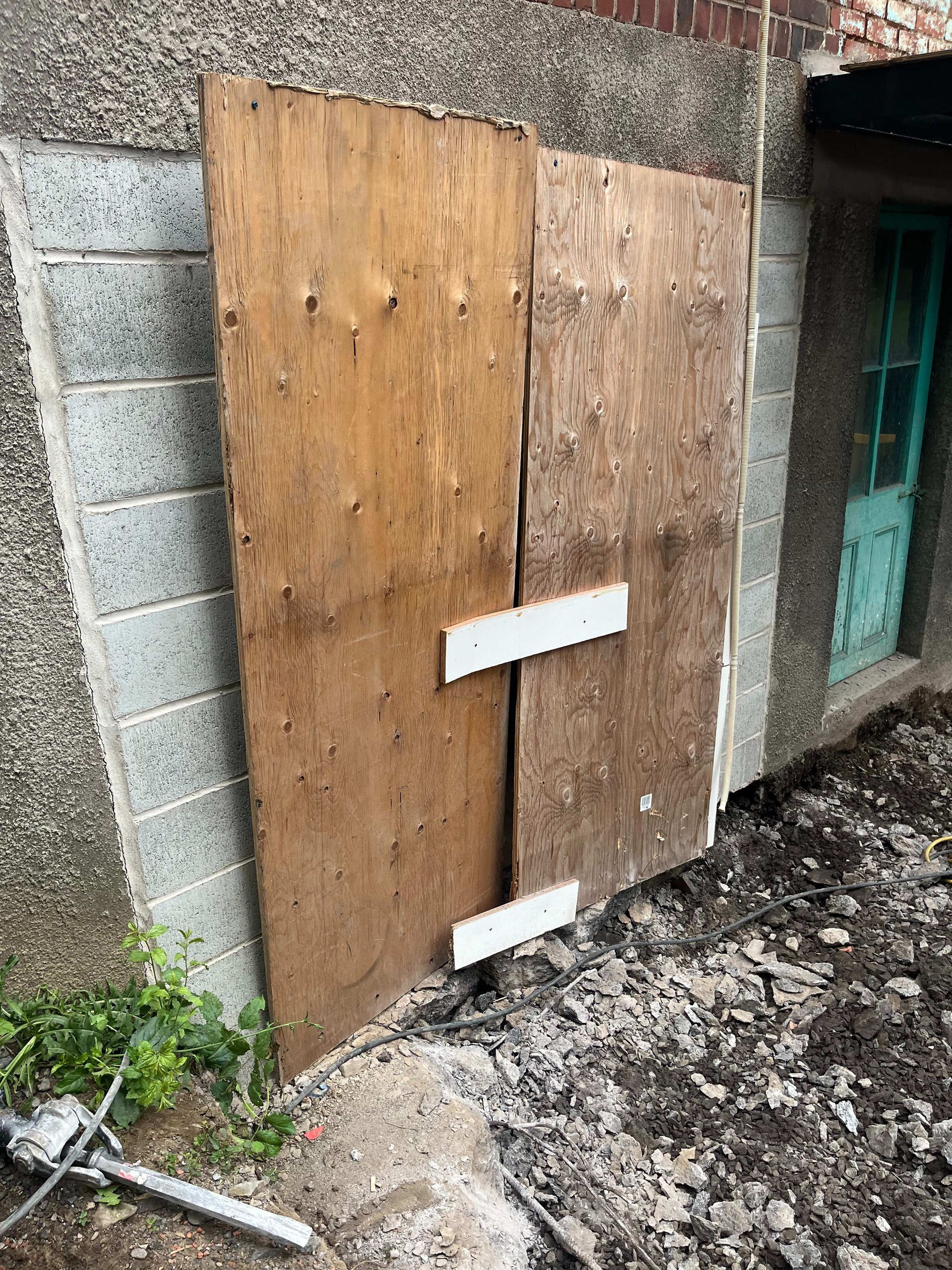A wooden door is sitting on the side of a building.
