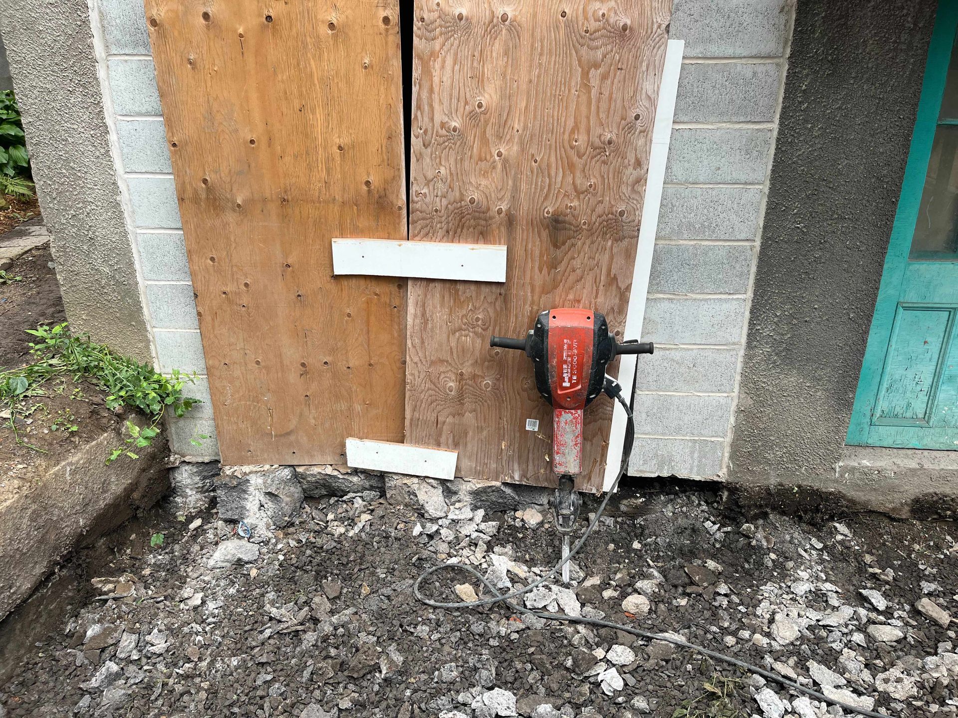A concrete wall with a wooden door and a hammer in front of it.