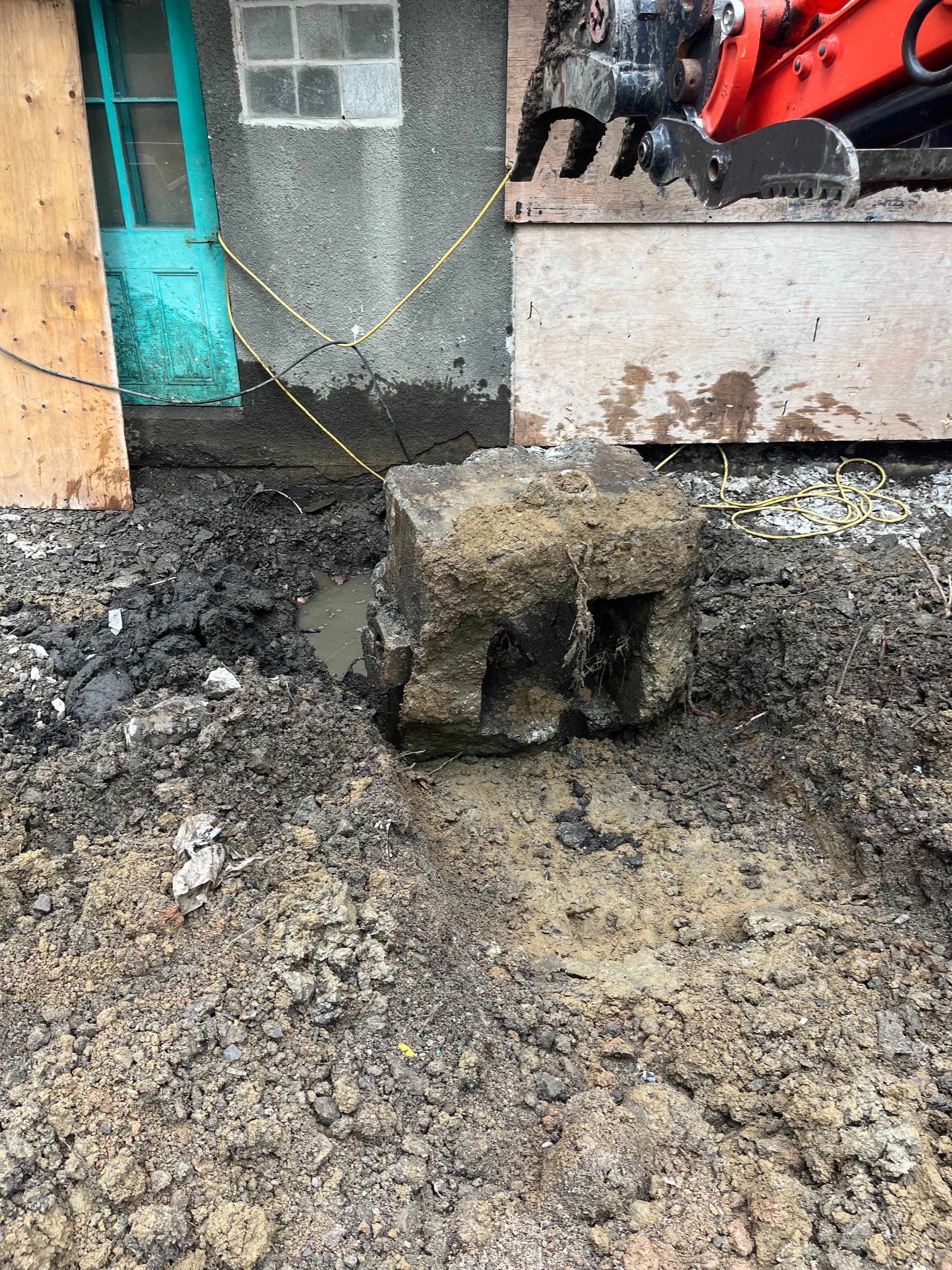 A large rock is sitting in the dirt in front of a building.