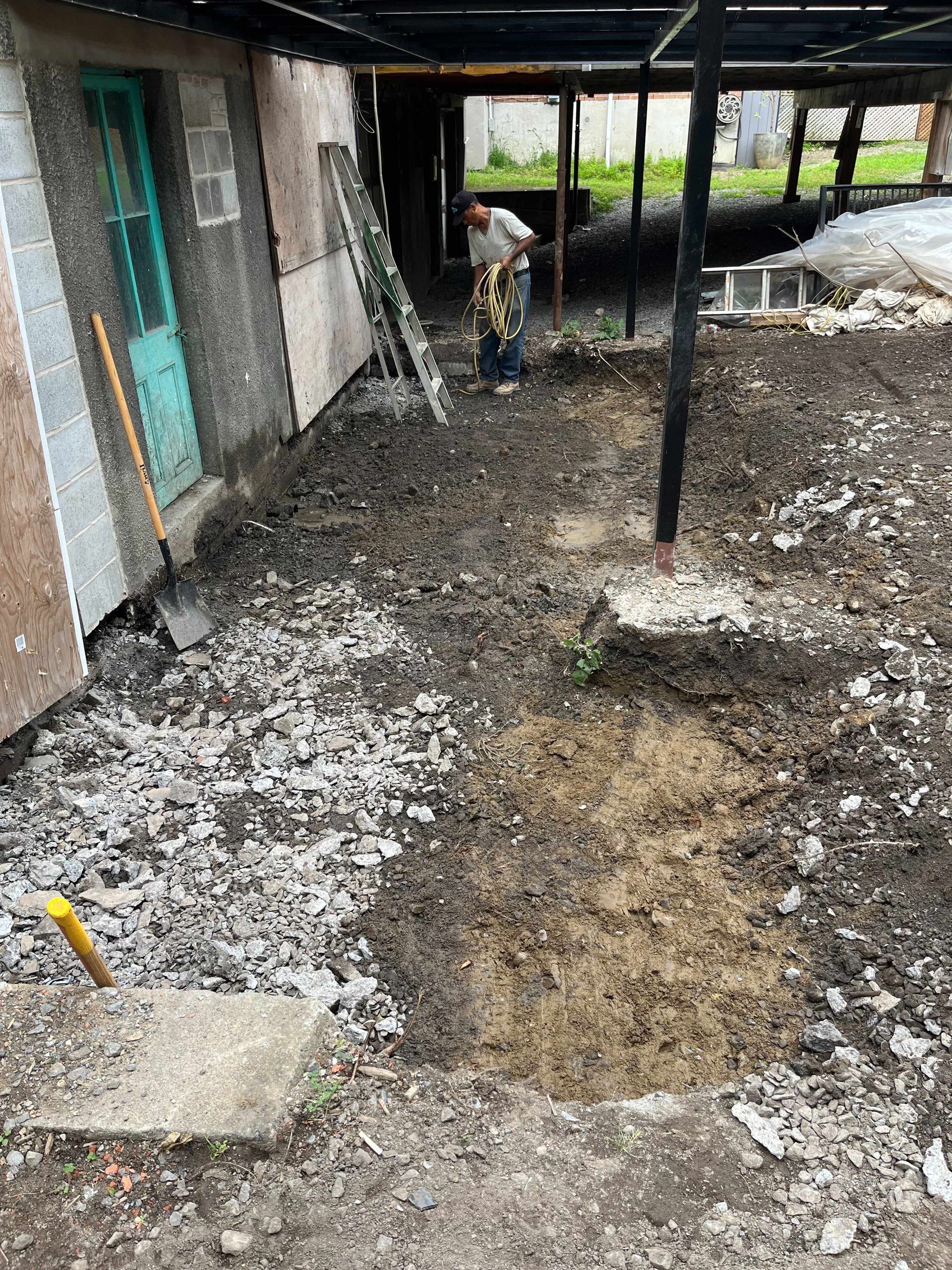 A man is digging a hole in the dirt in front of a house.