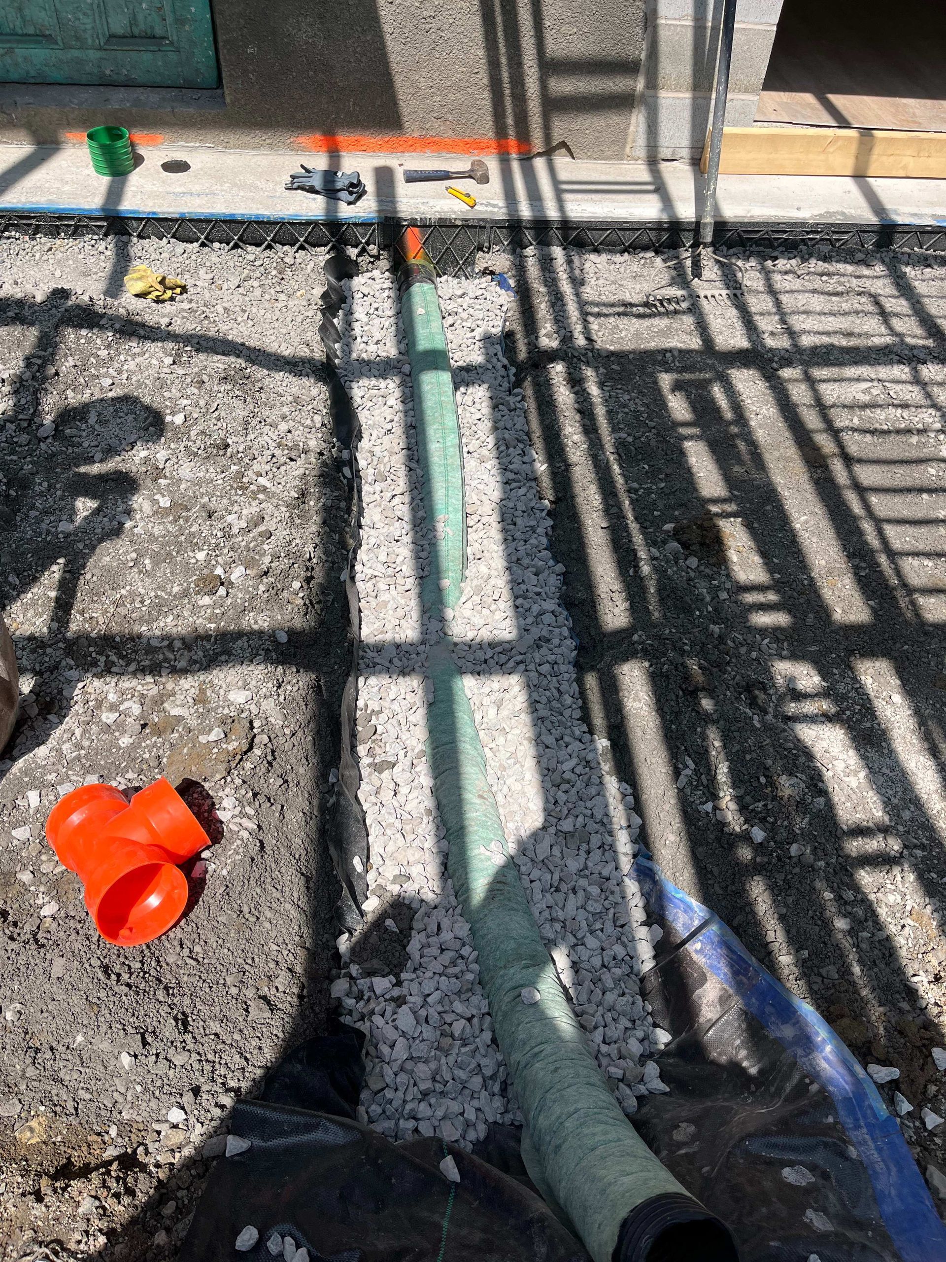 A green pipe is sitting on top of a pile of gravel.