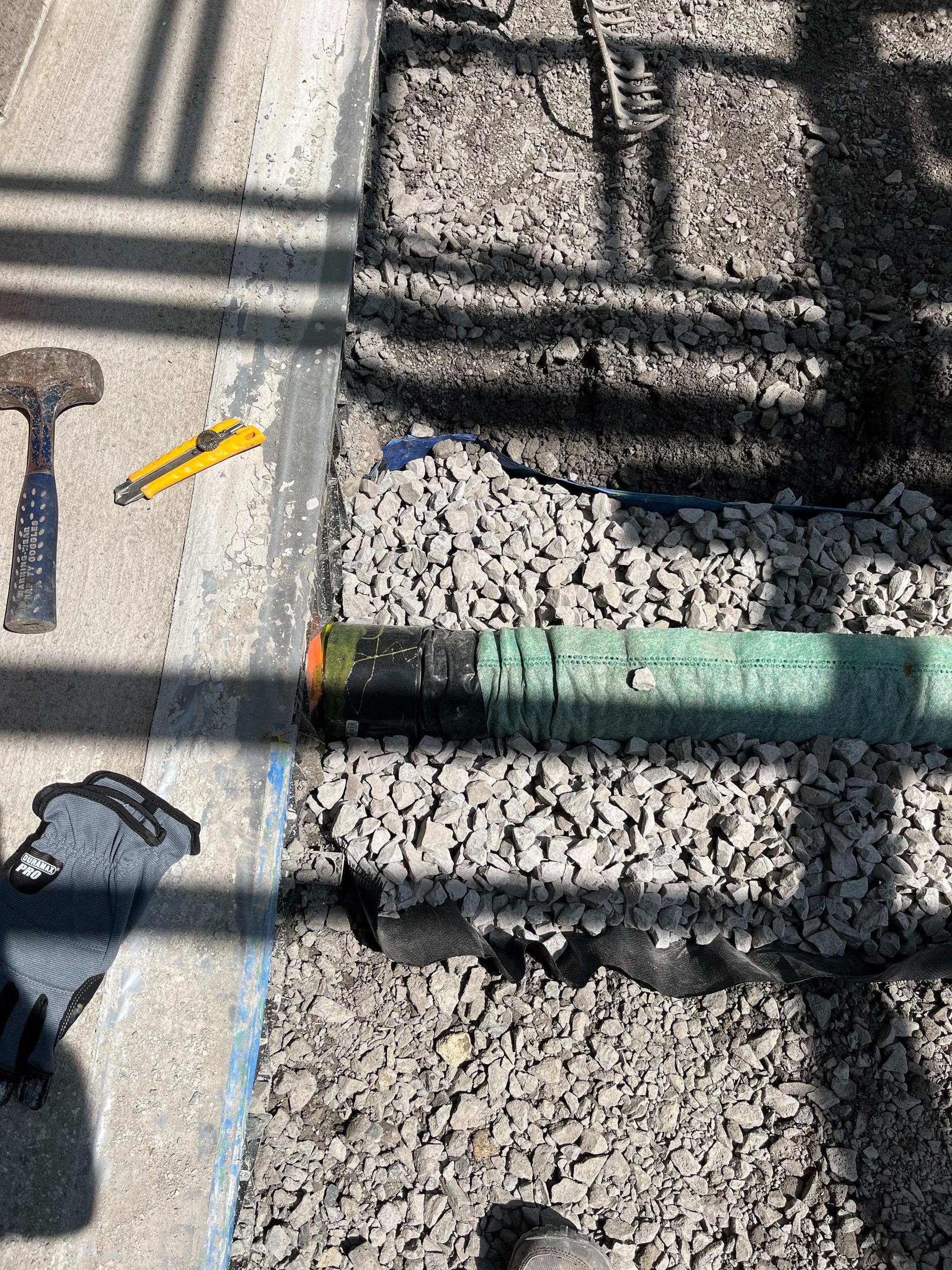A person is working on a pipe on the ground.