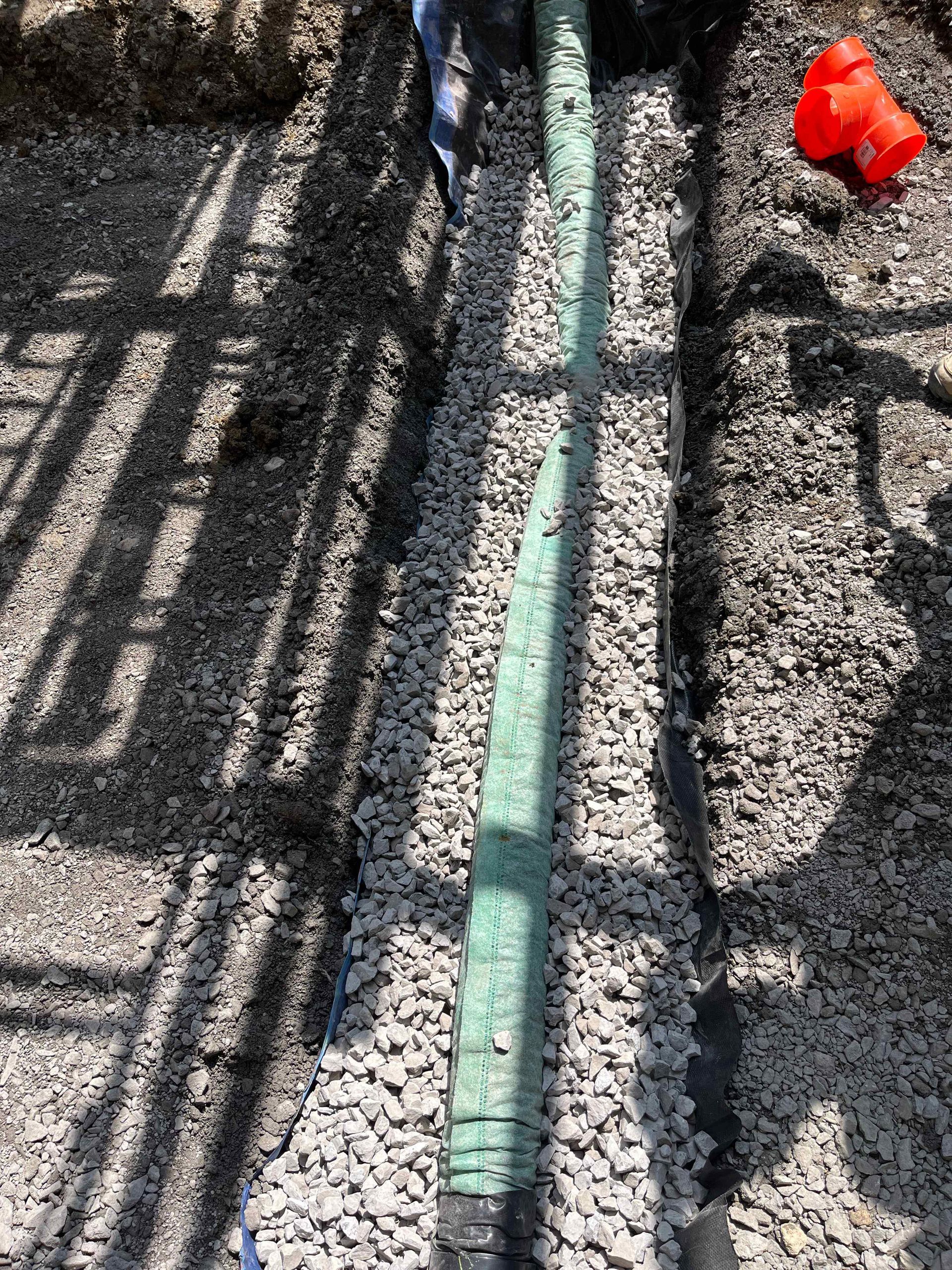 A green pipe is sitting on top of a pile of gravel.
