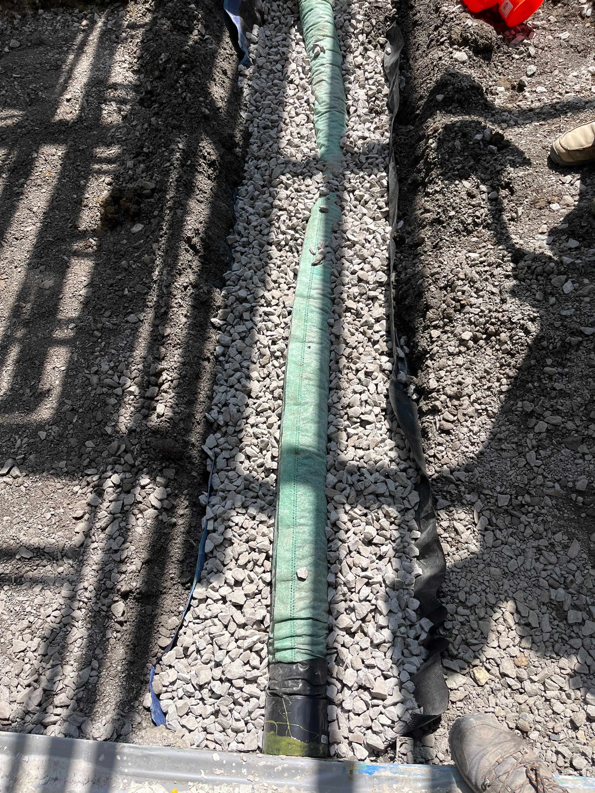 A green pipe is sitting on top of a pile of gravel.