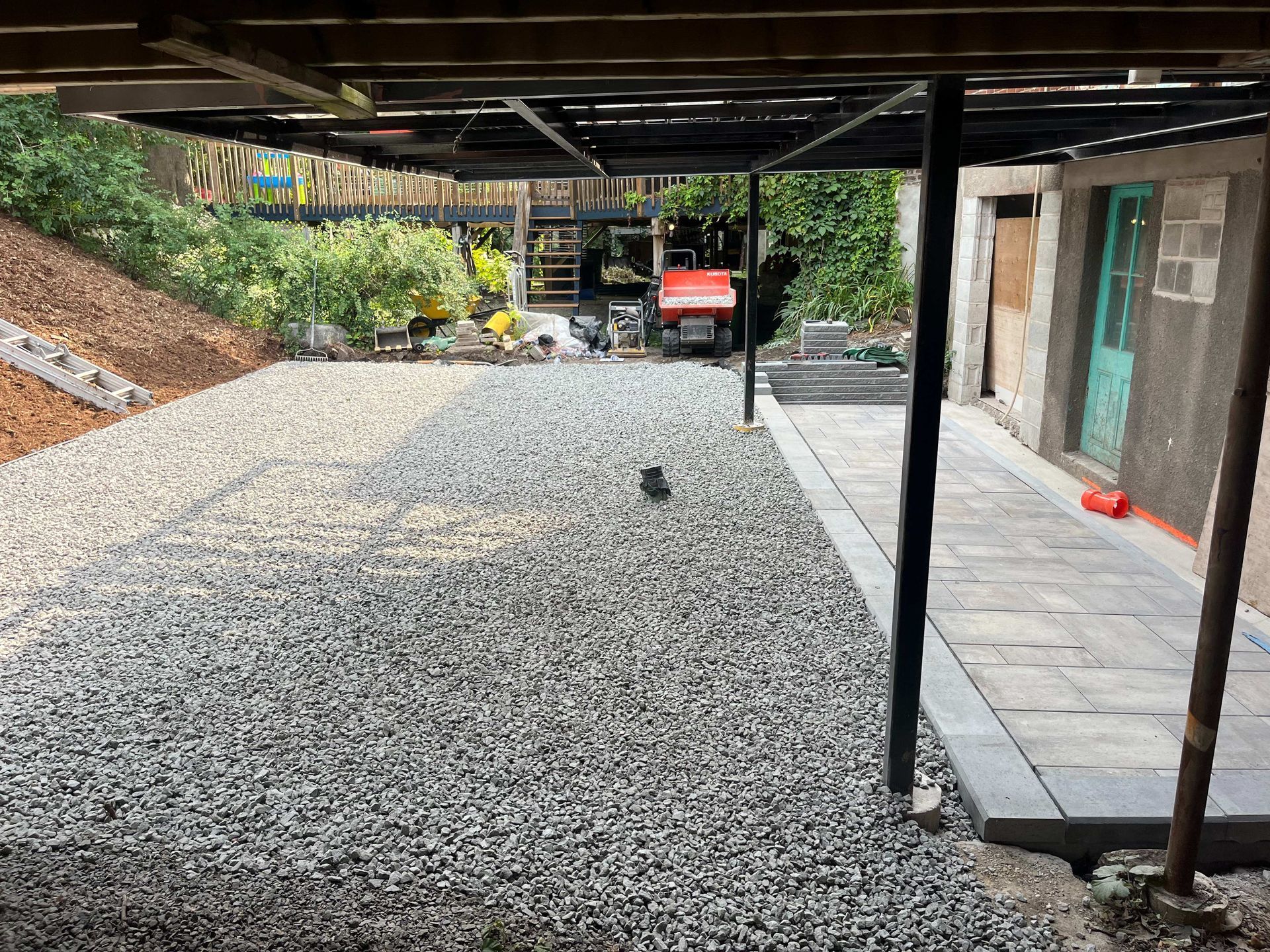 A gravel driveway leading to a garage under a building.