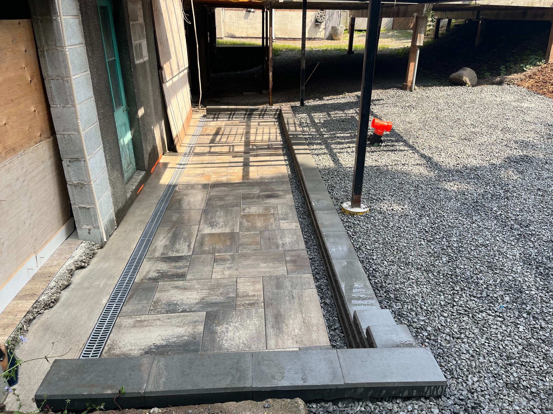 A stone walkway is being built in a gravel area.