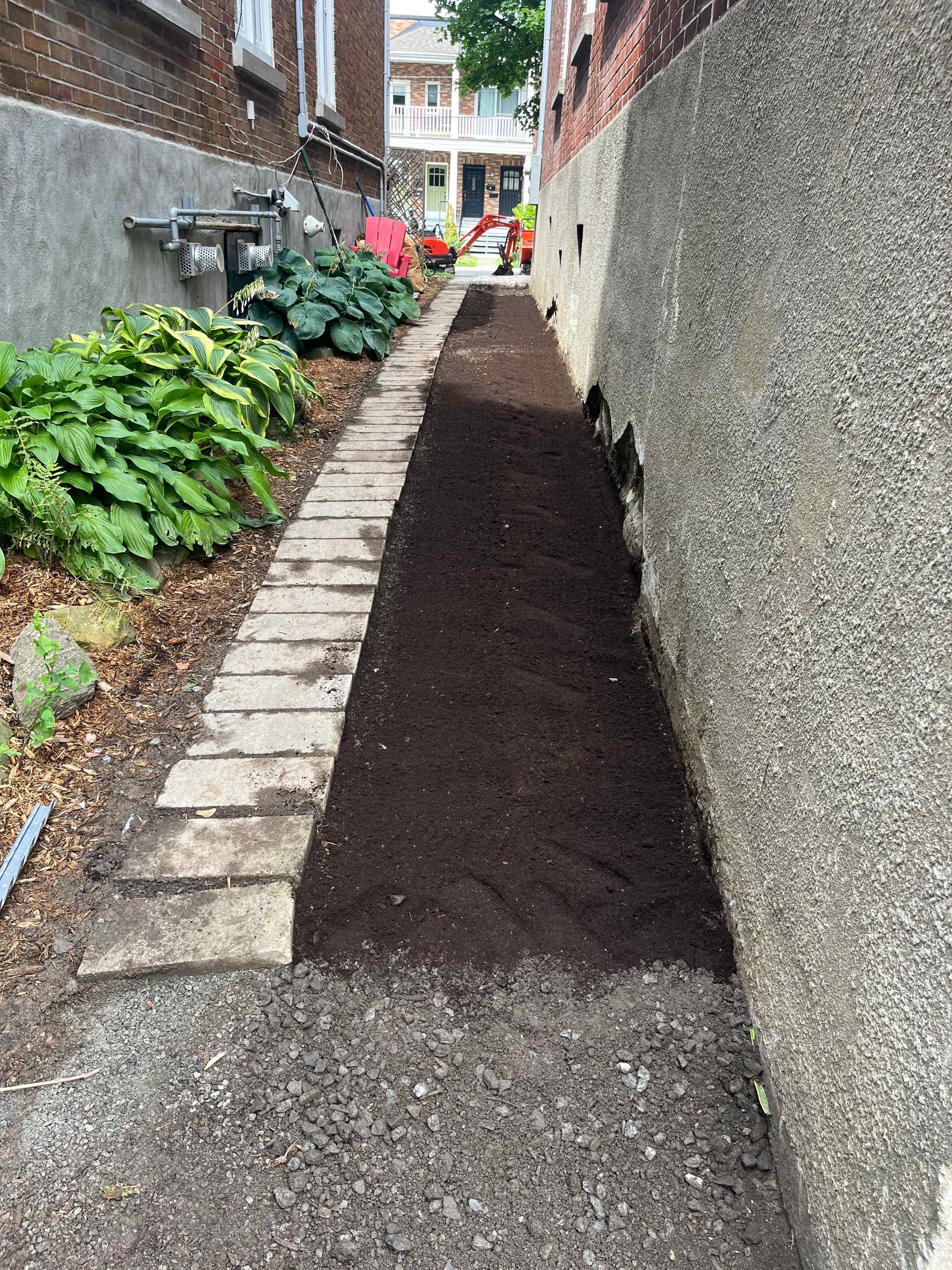 A sidewalk with a lot of dirt between two buildings.