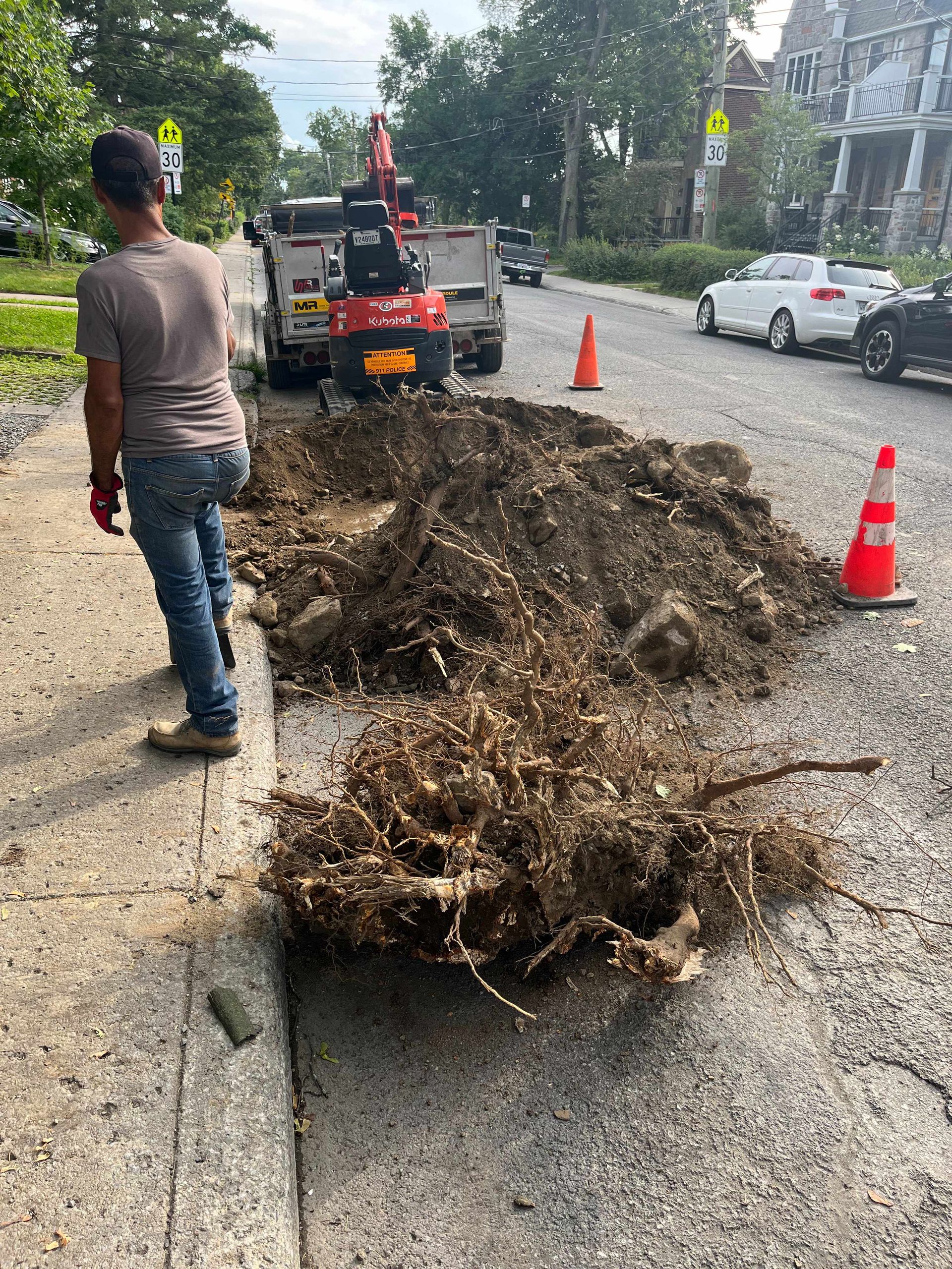 A man is walking down a sidewalk next to a pile of dirt.