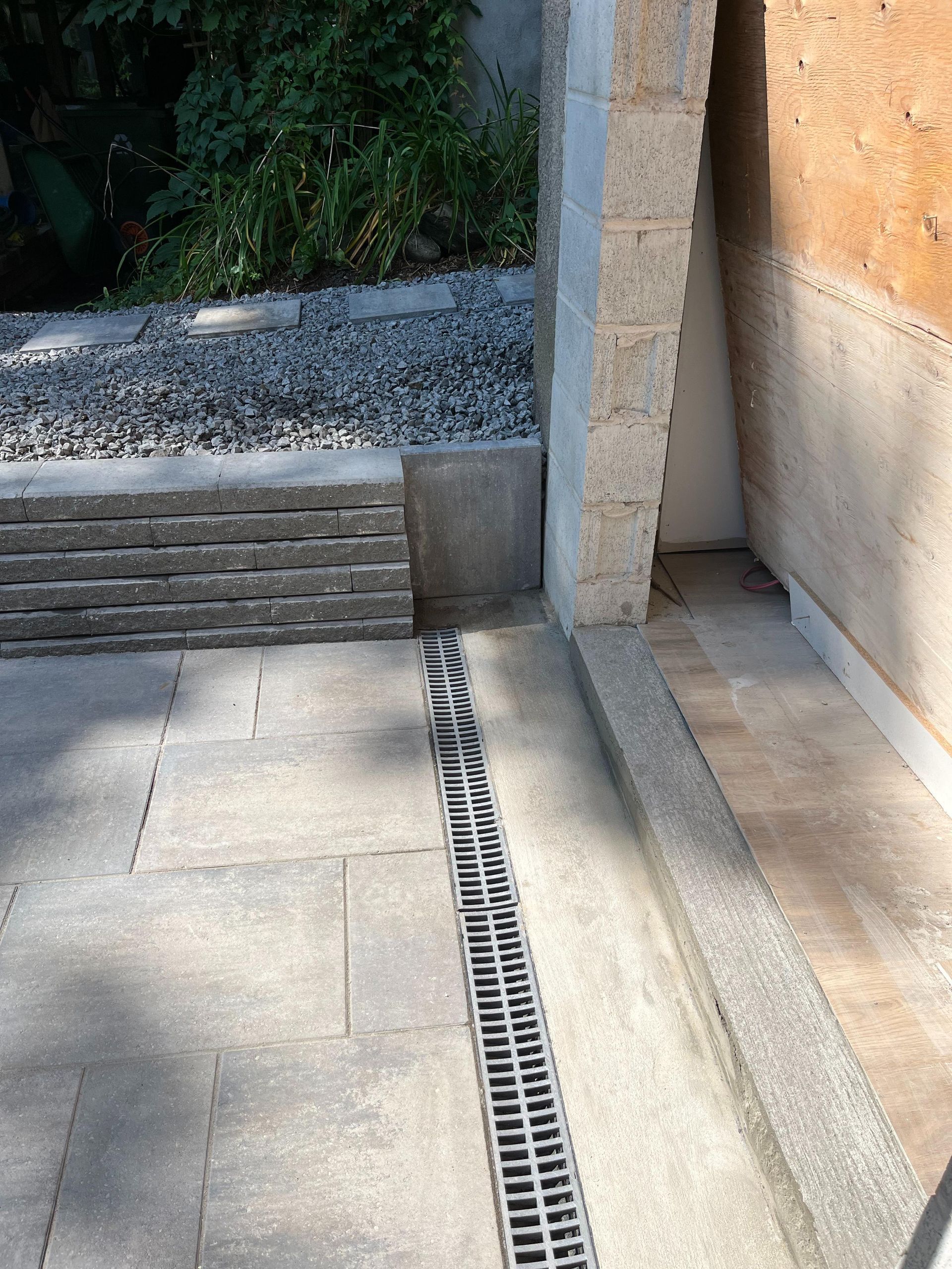 A drain on a sidewalk next to a brick wall