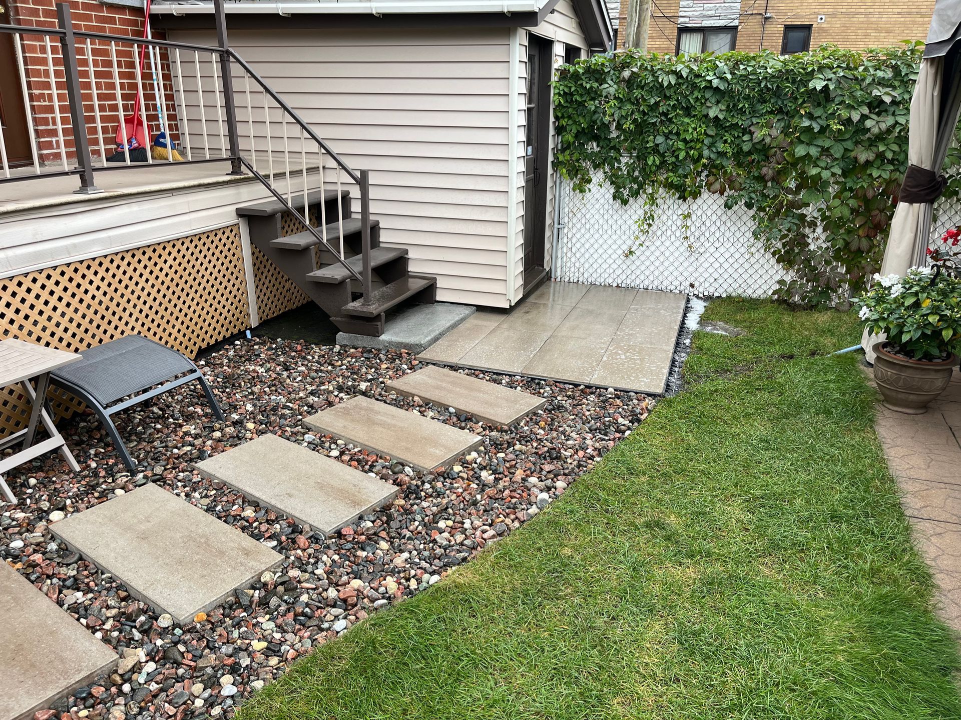 A backyard with stairs leading up to a shed and a table and chairs.