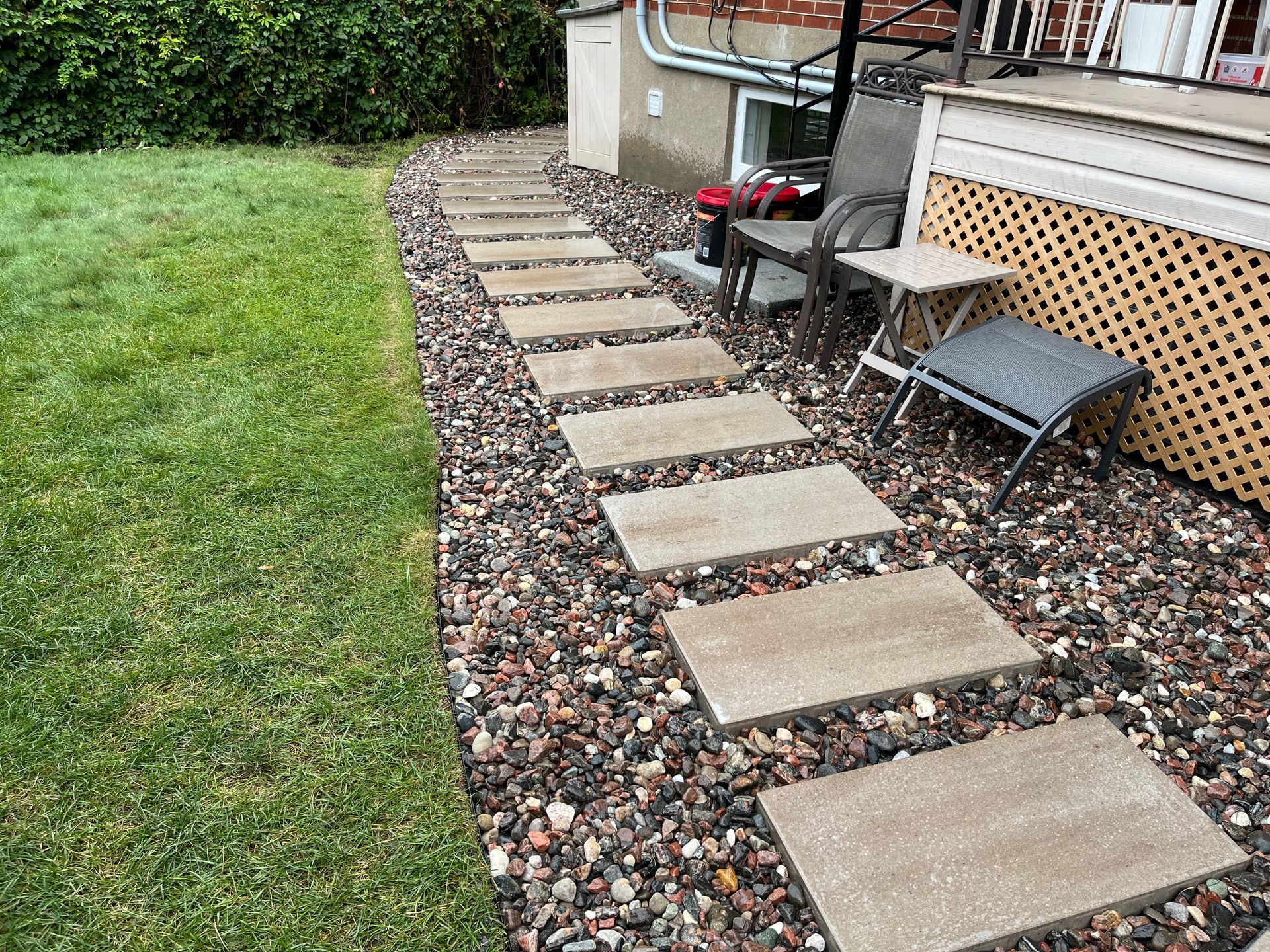 A stone walkway leading to a patio with chairs and tables.