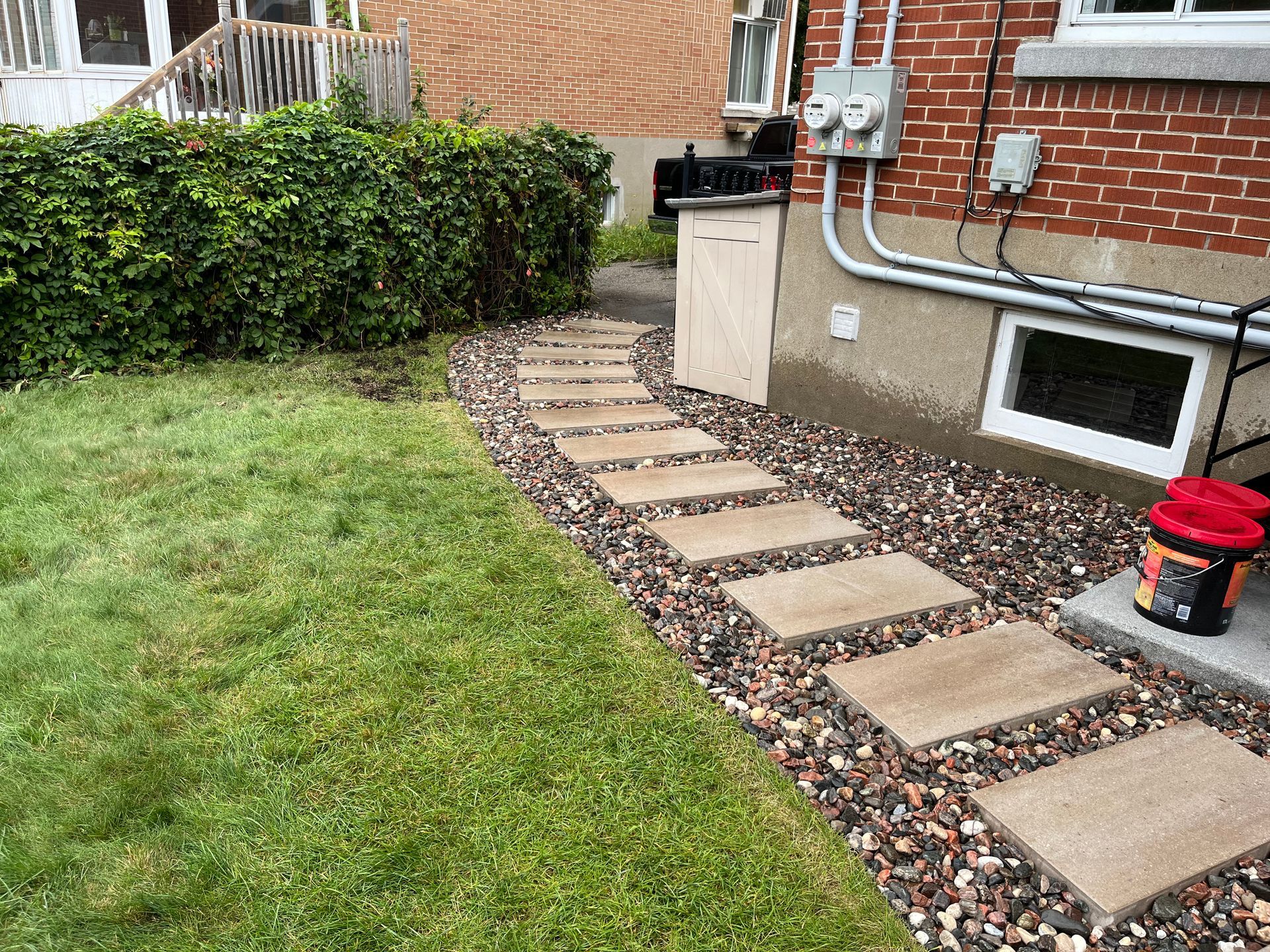 A stone walkway leading to a brick house in a backyard.