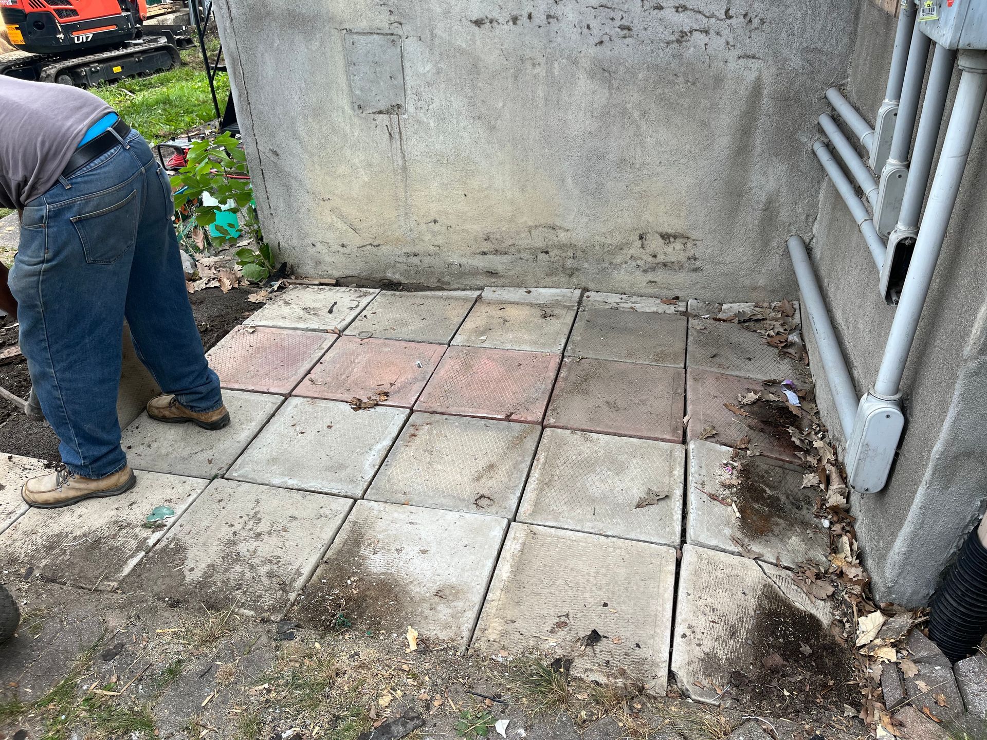 A man is standing on a tiled floor next to a wall.