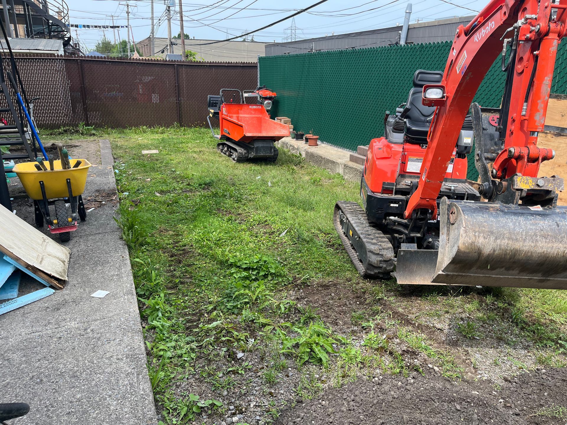 A red excavator is digging a hole in a yard.