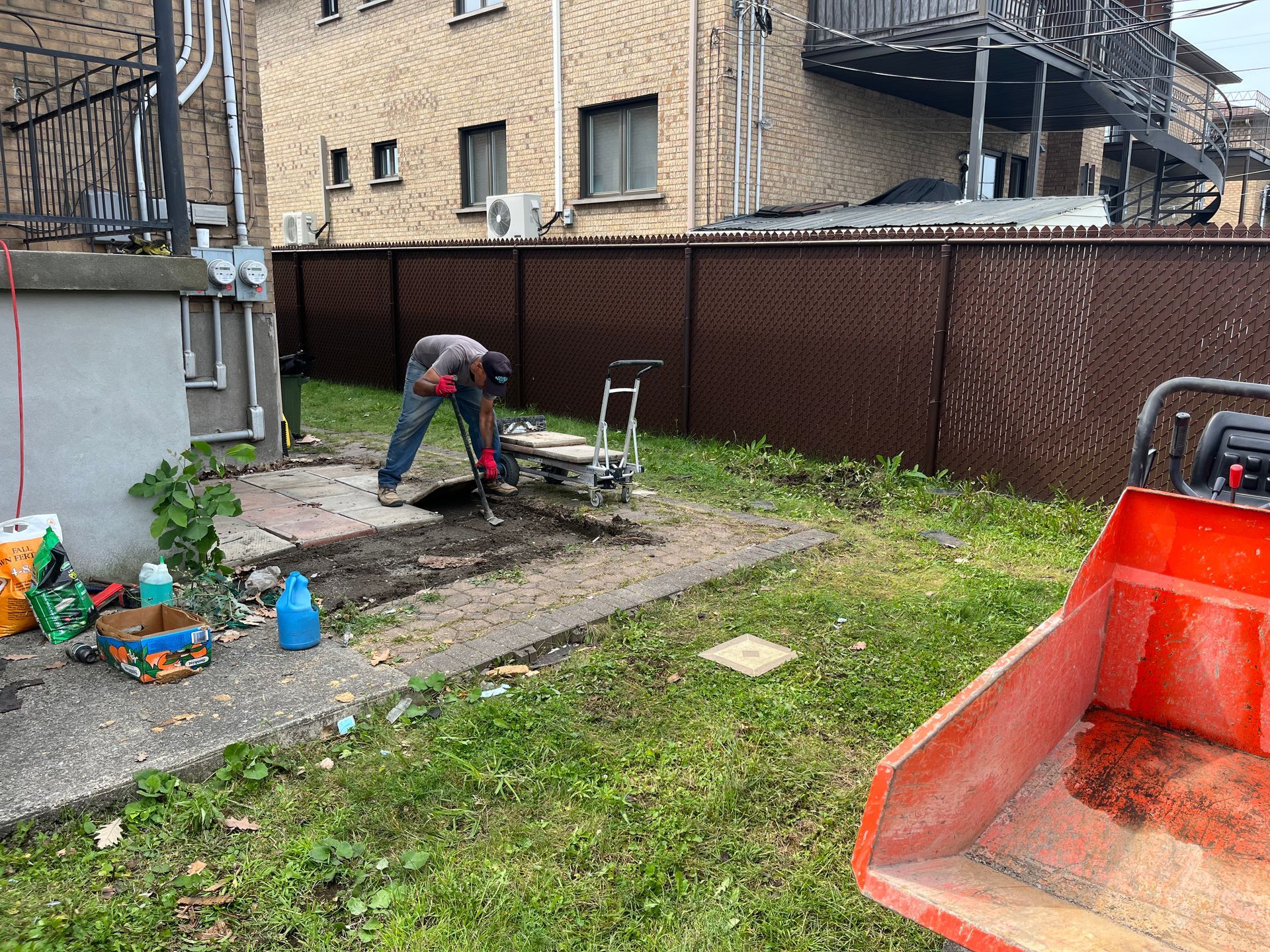 A man is digging in the dirt in a backyard.