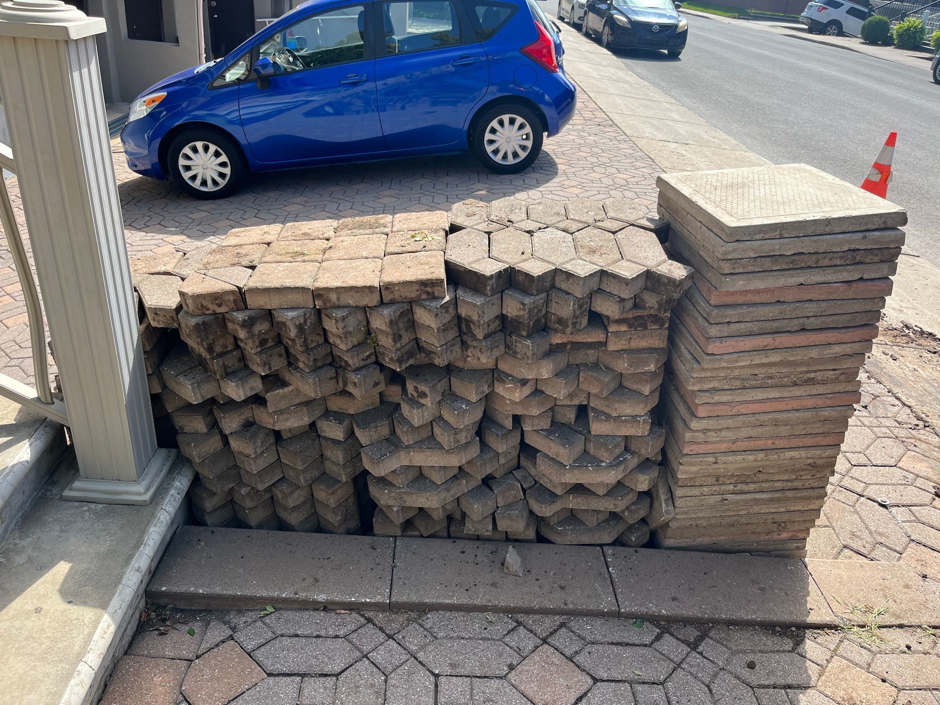 A blue car is parked next to a pile of bricks.