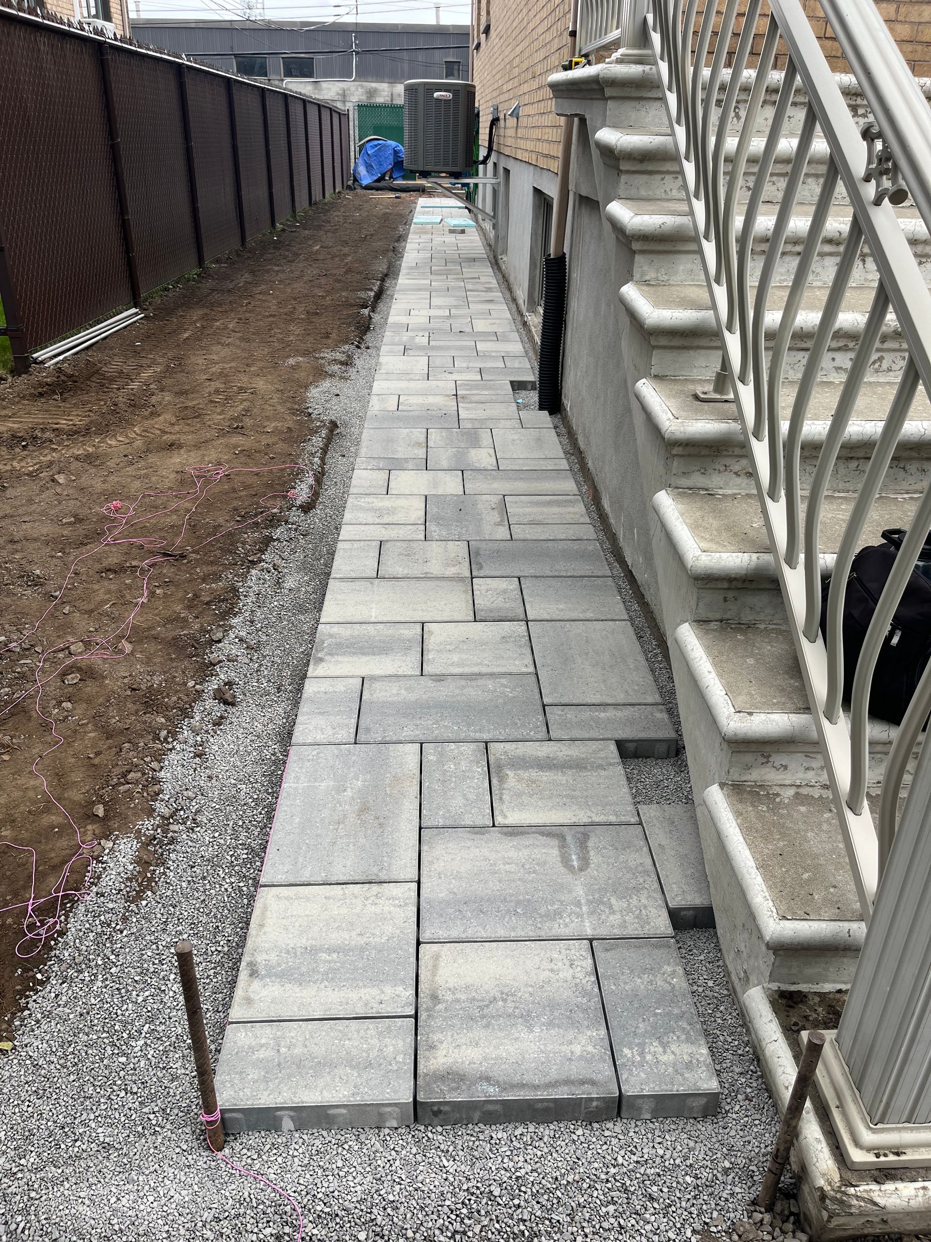 A sidewalk is being built next to a house with stairs.