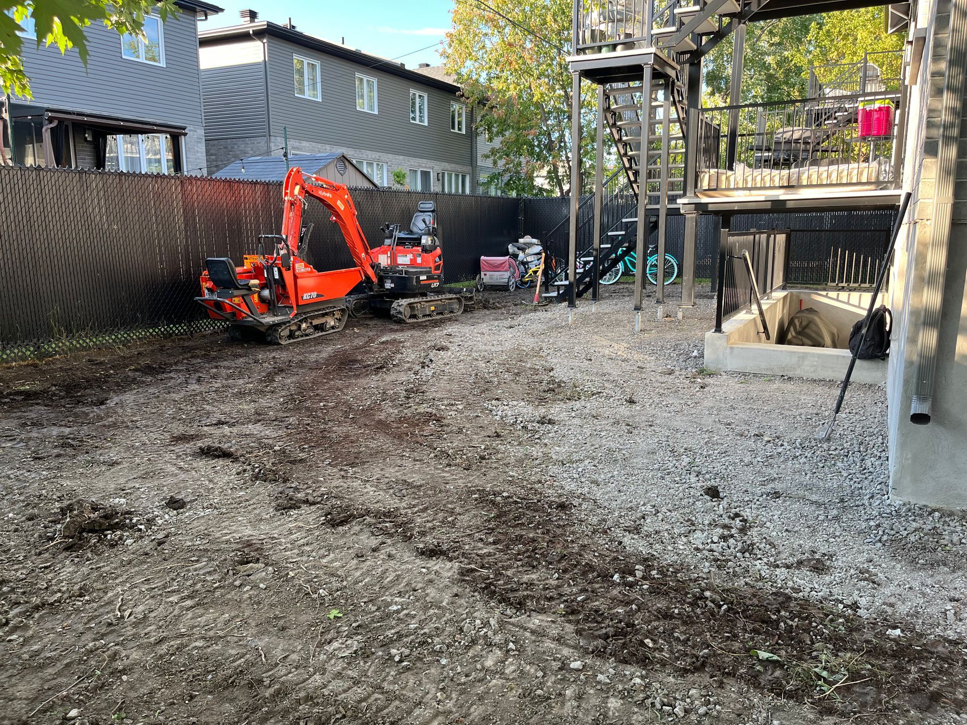 An excavator is sitting in the middle of a dirt field.