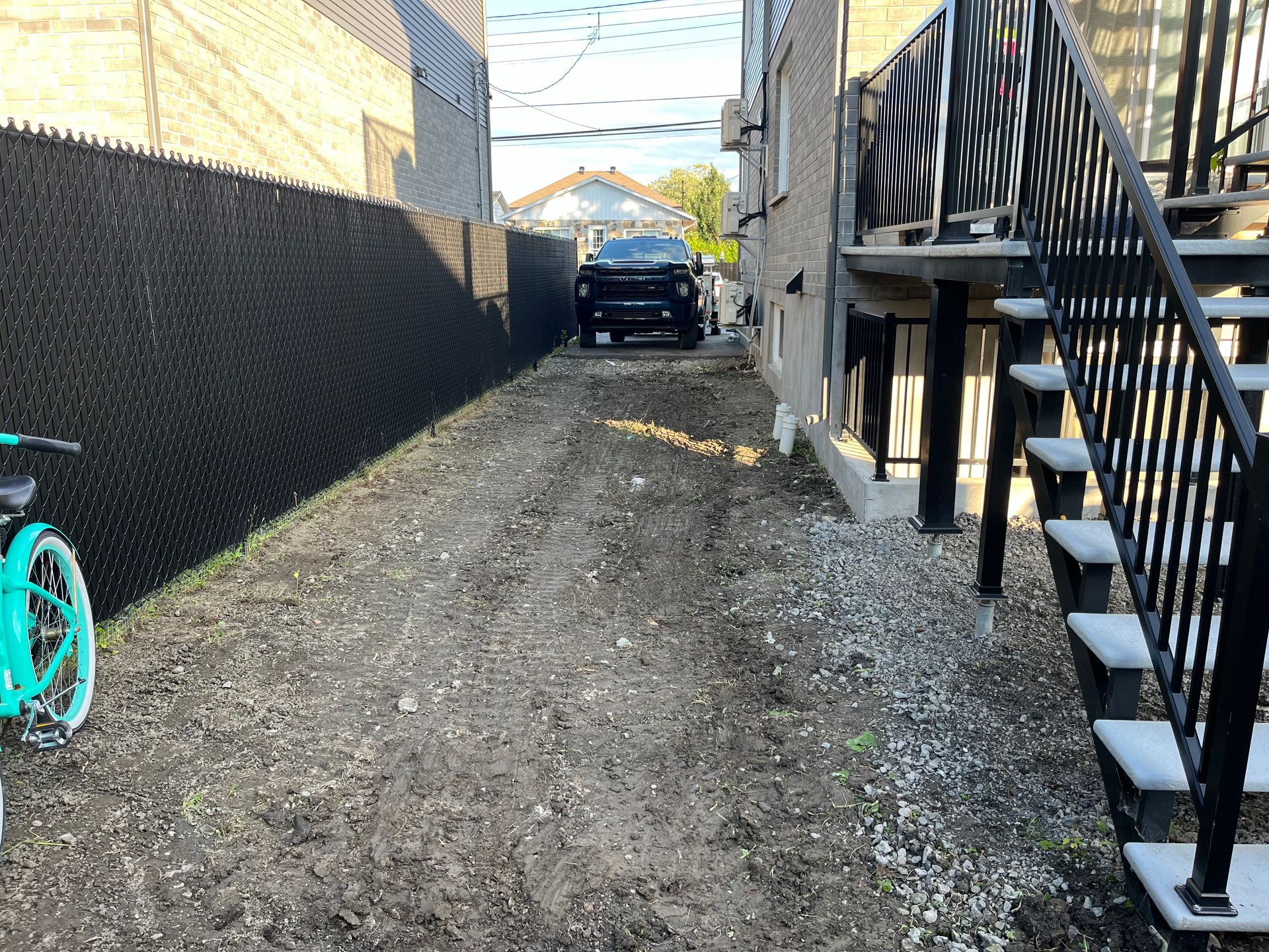 A bicycle is parked on the side of a dirt road next to a staircase.