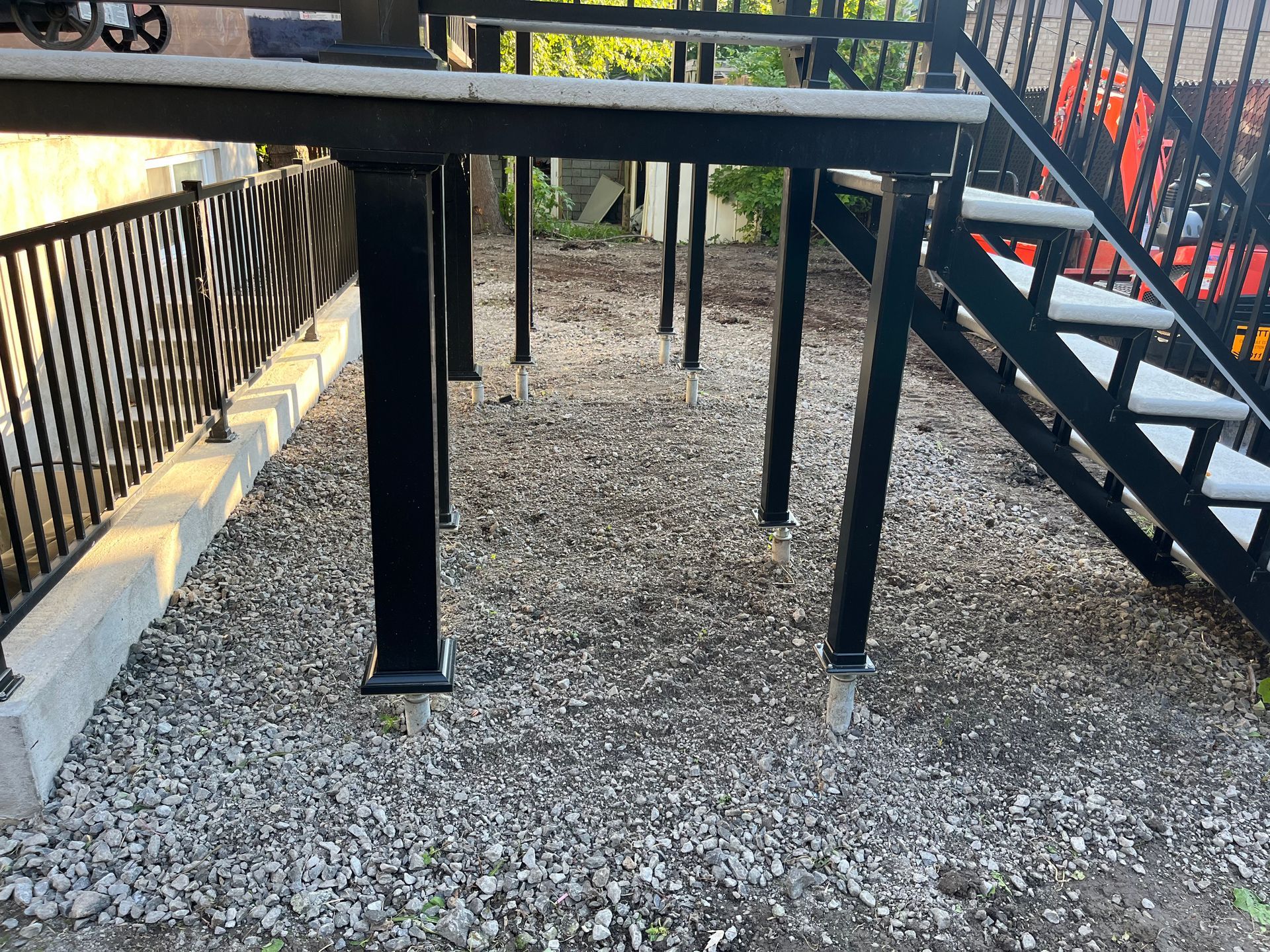 A deck with stairs leading up to it and a fence in the background.