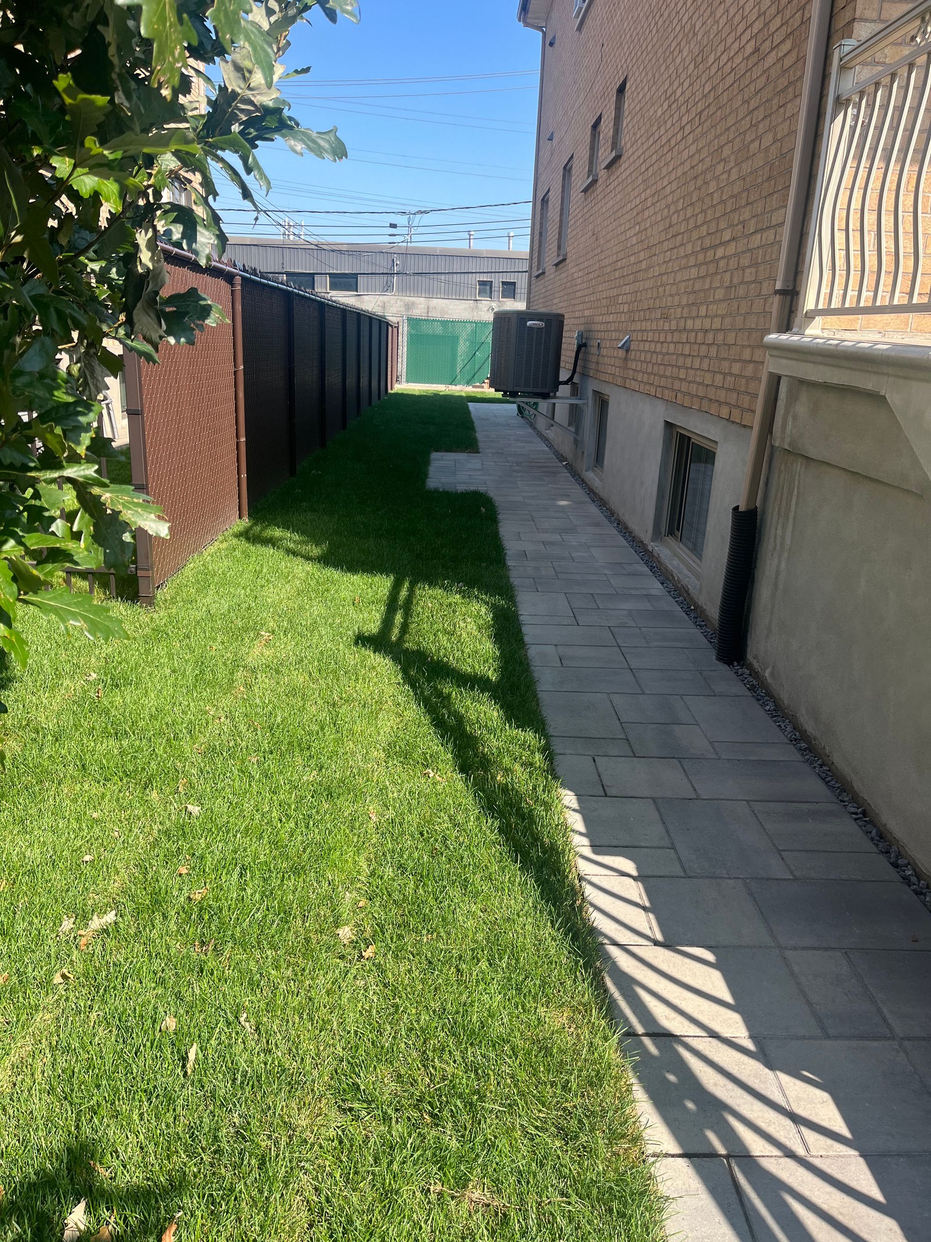 A sidewalk leading to a grassy yard next to a brick building.