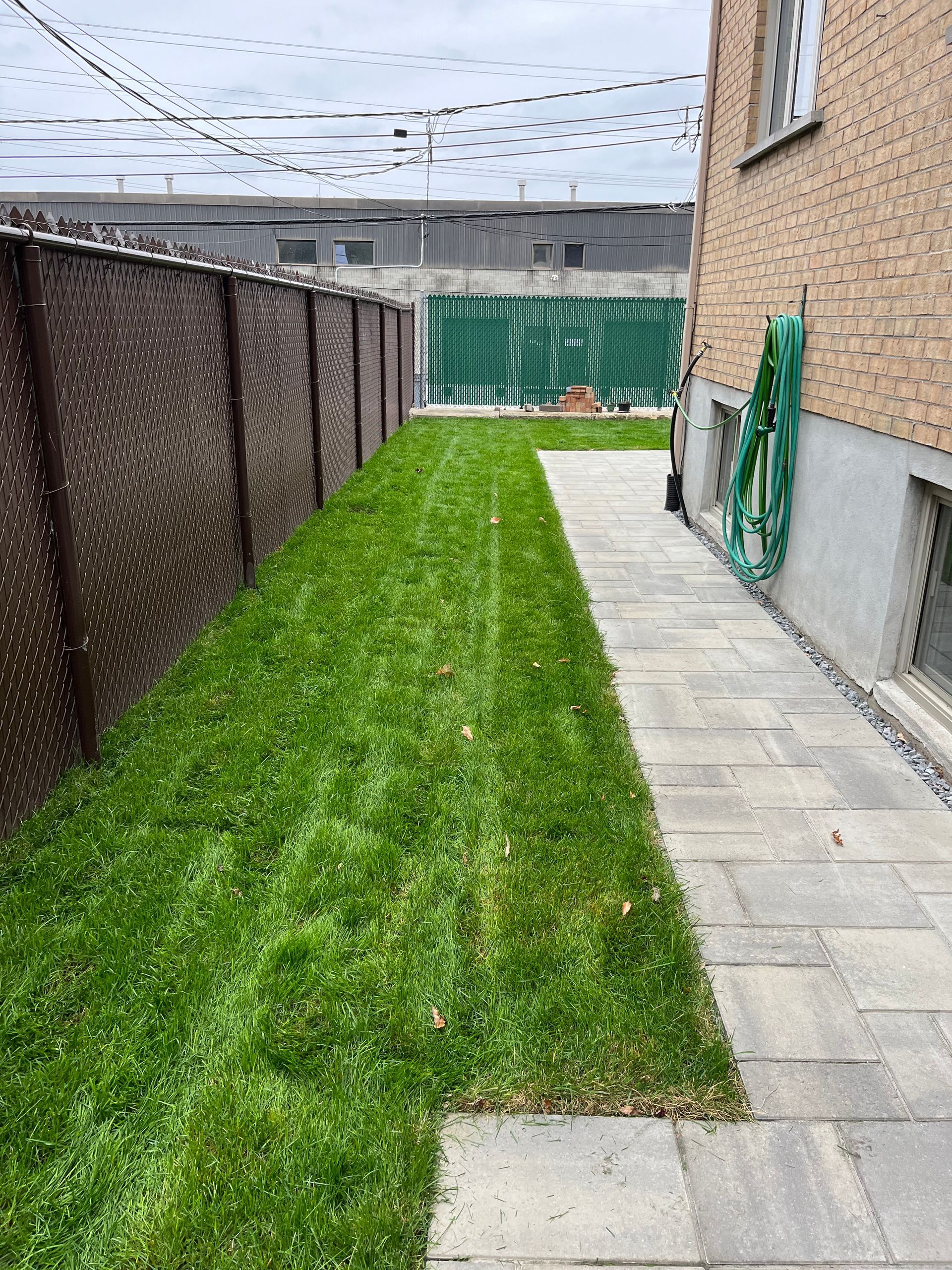A backyard with a fence and a walkway leading to it.