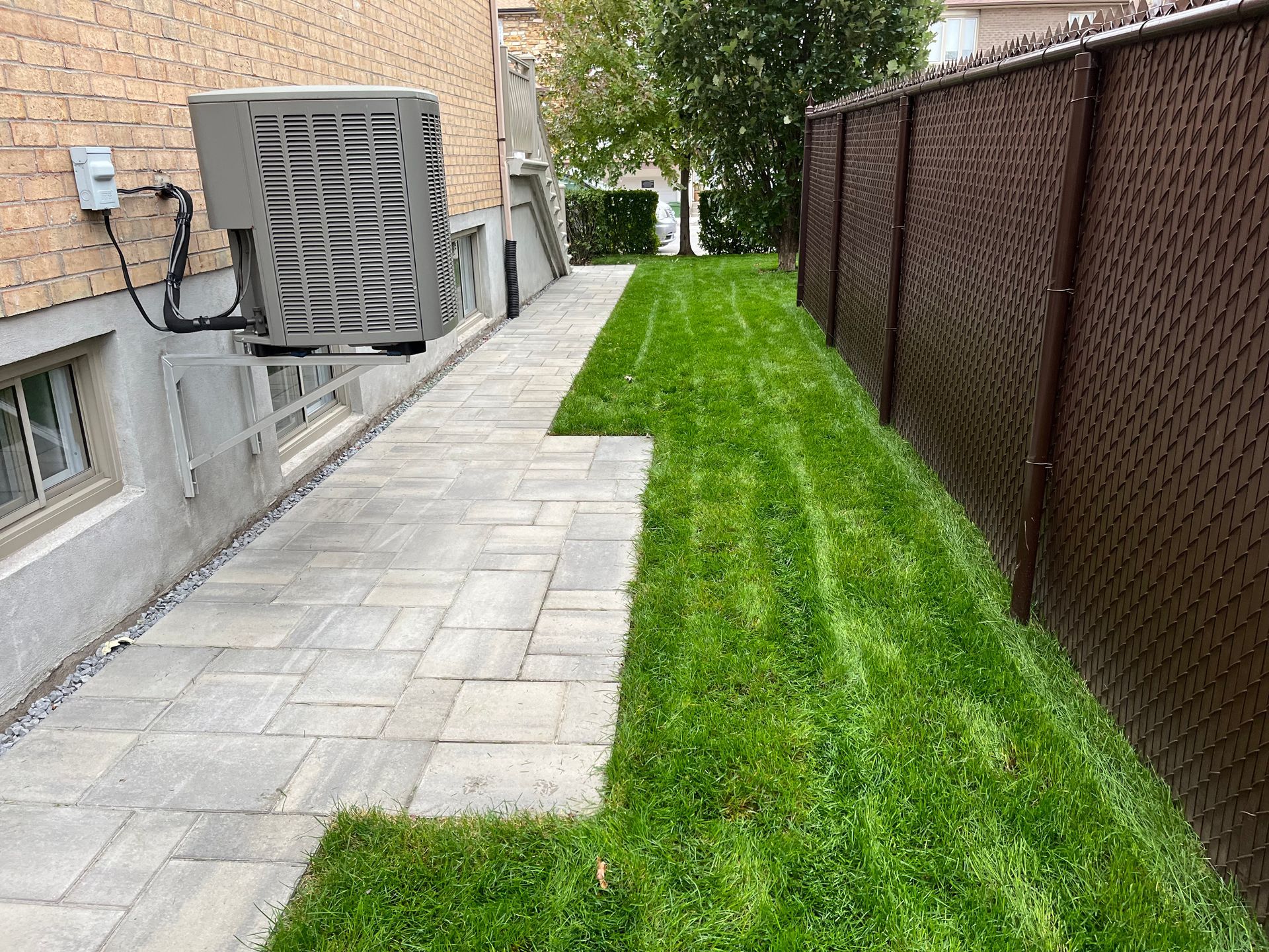 A walkway leading to a backyard with a chain link fence.