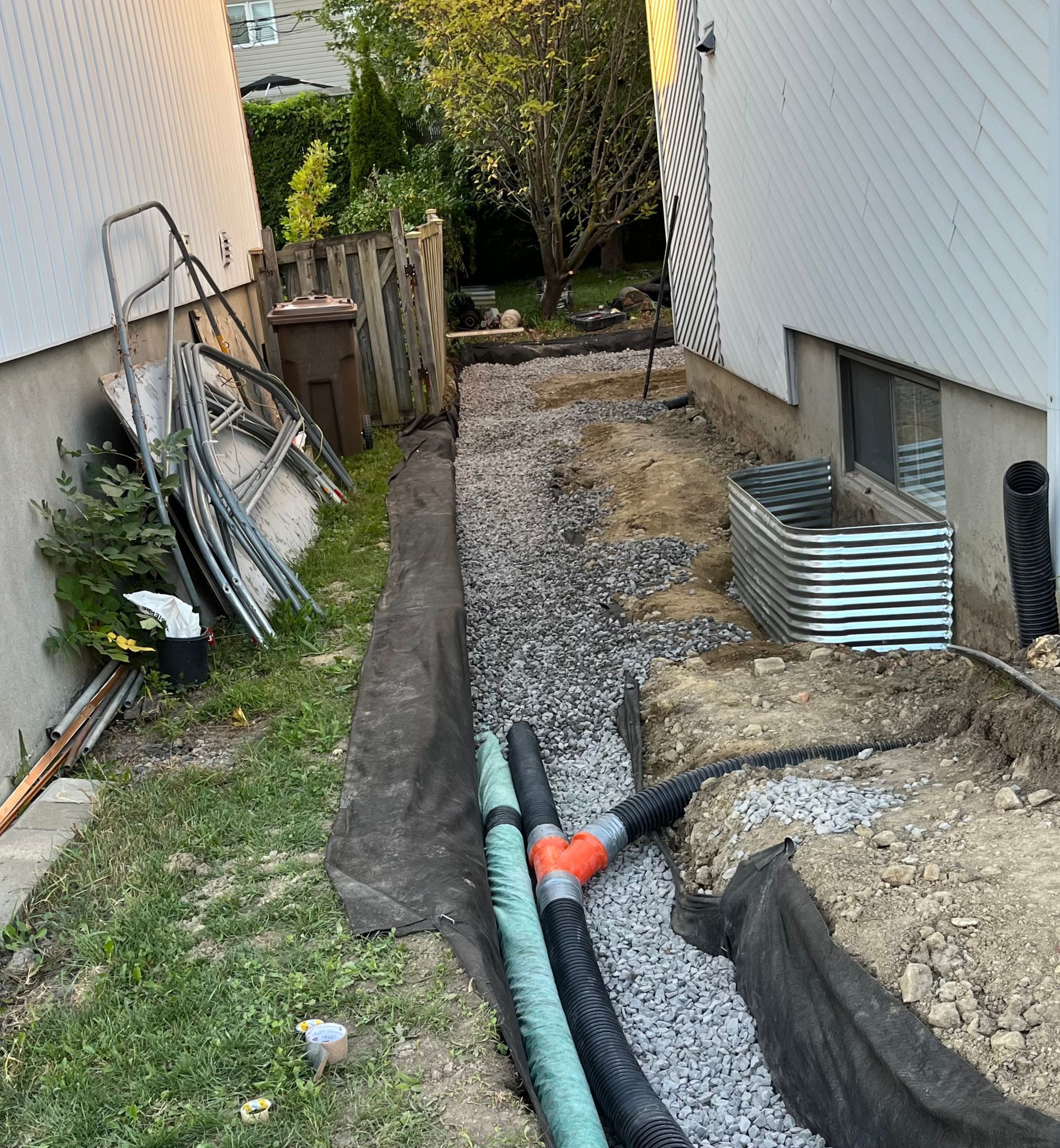 A drainage system is being installed in the backyard of a house.