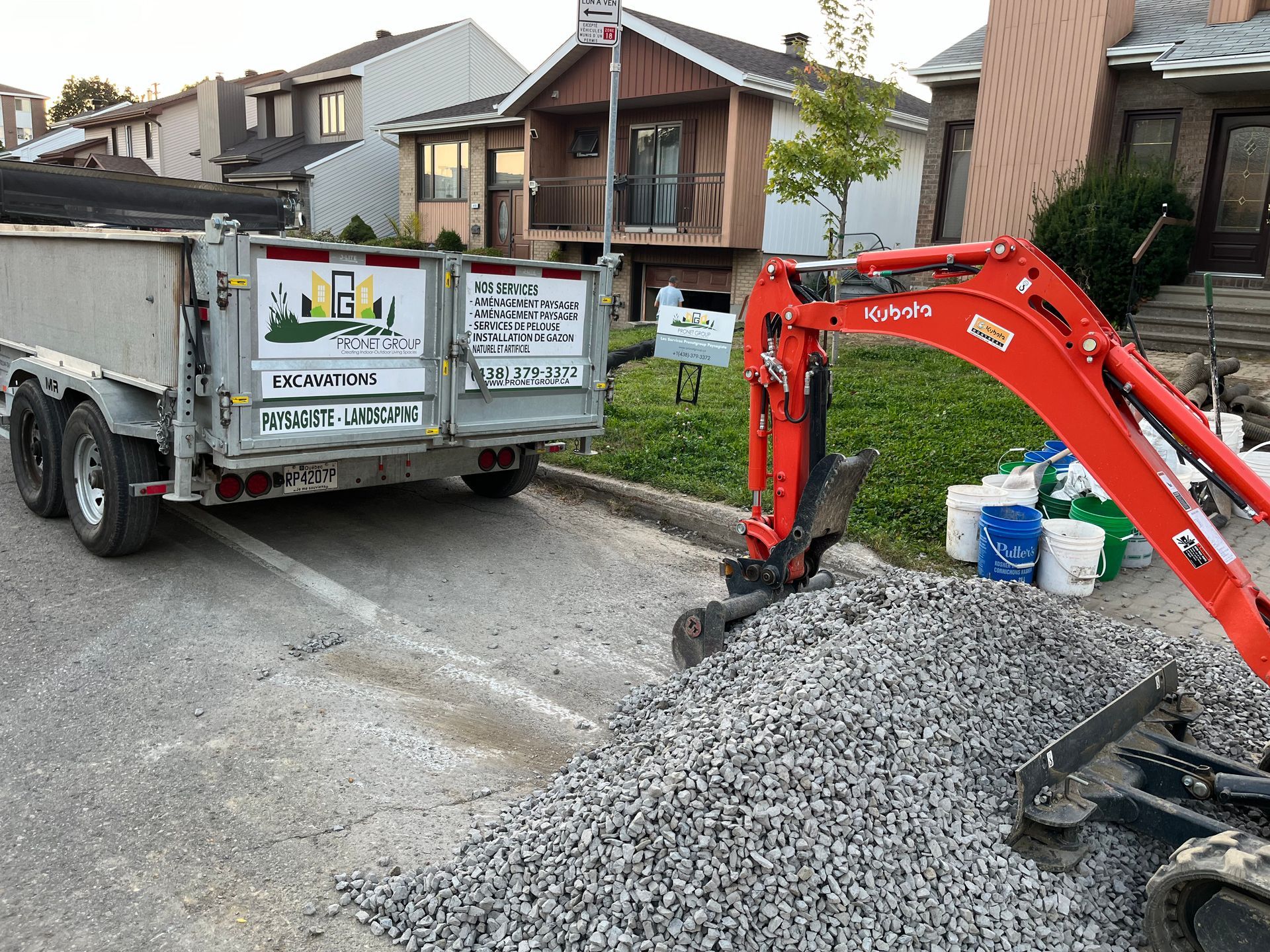 A dump truck is parked on the side of the road next to a small excavator.