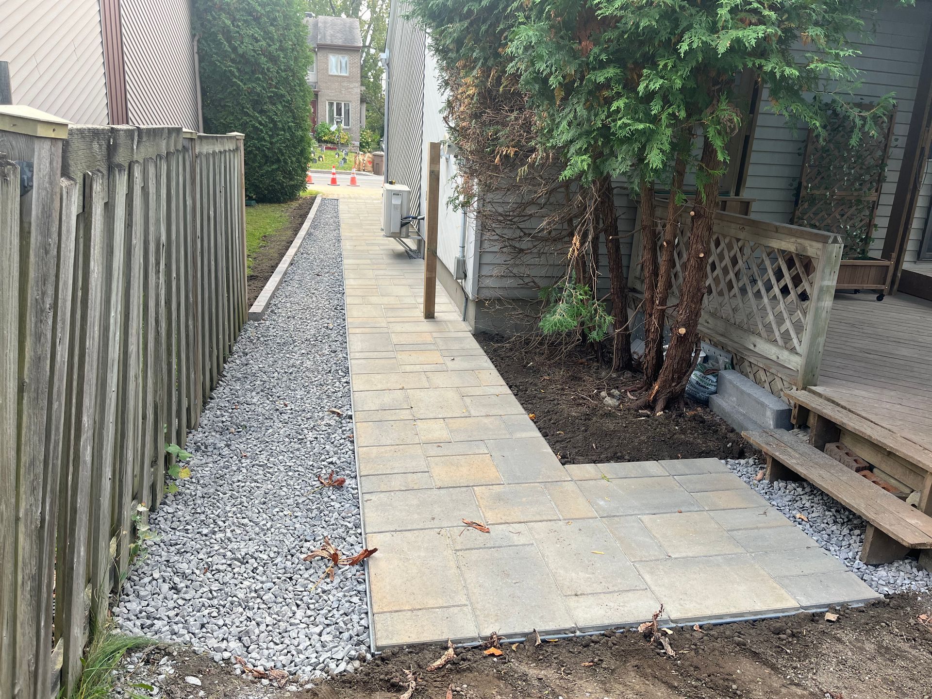 A stone walkway leading to a house next to a wooden fence.