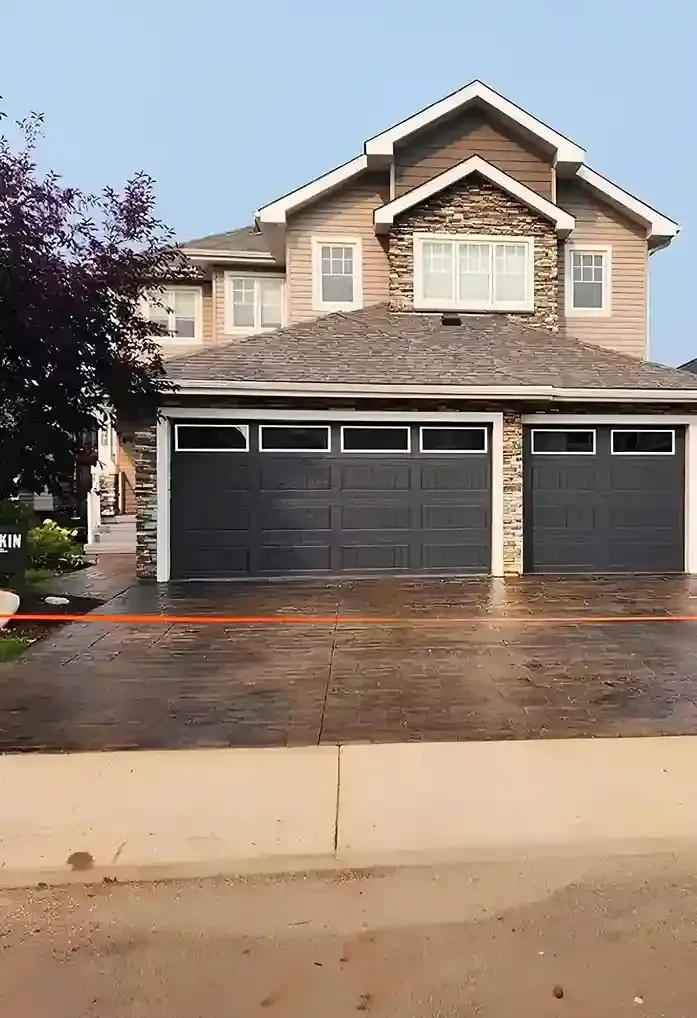 A large house with two garage doors and a driveway.
