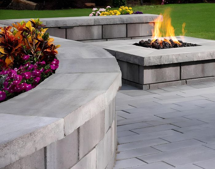 A fire pit is surrounded by bricks and flowers