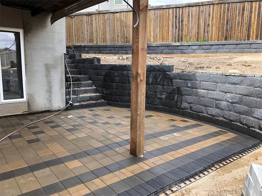 A patio with a brick wall and a wooden fence in the background.