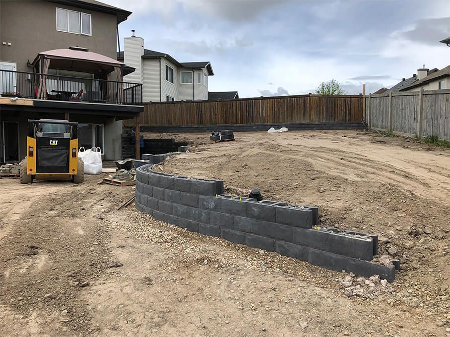A brick wall is being built in the backyard of a house.